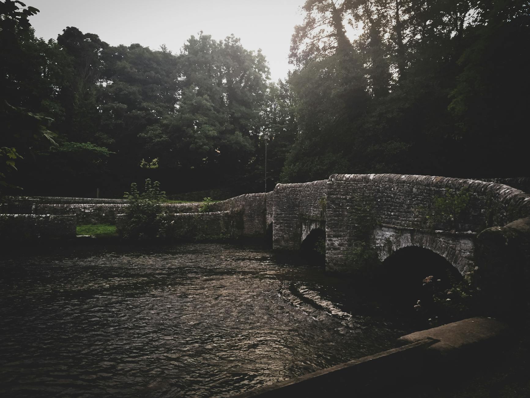 An ancient stone bridge over a gentle river in an English village