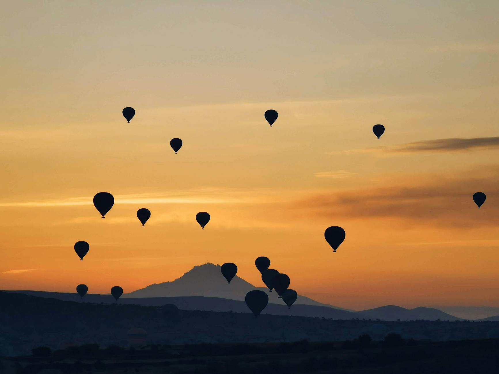 A hot air balloon floating over the countryside at sunset