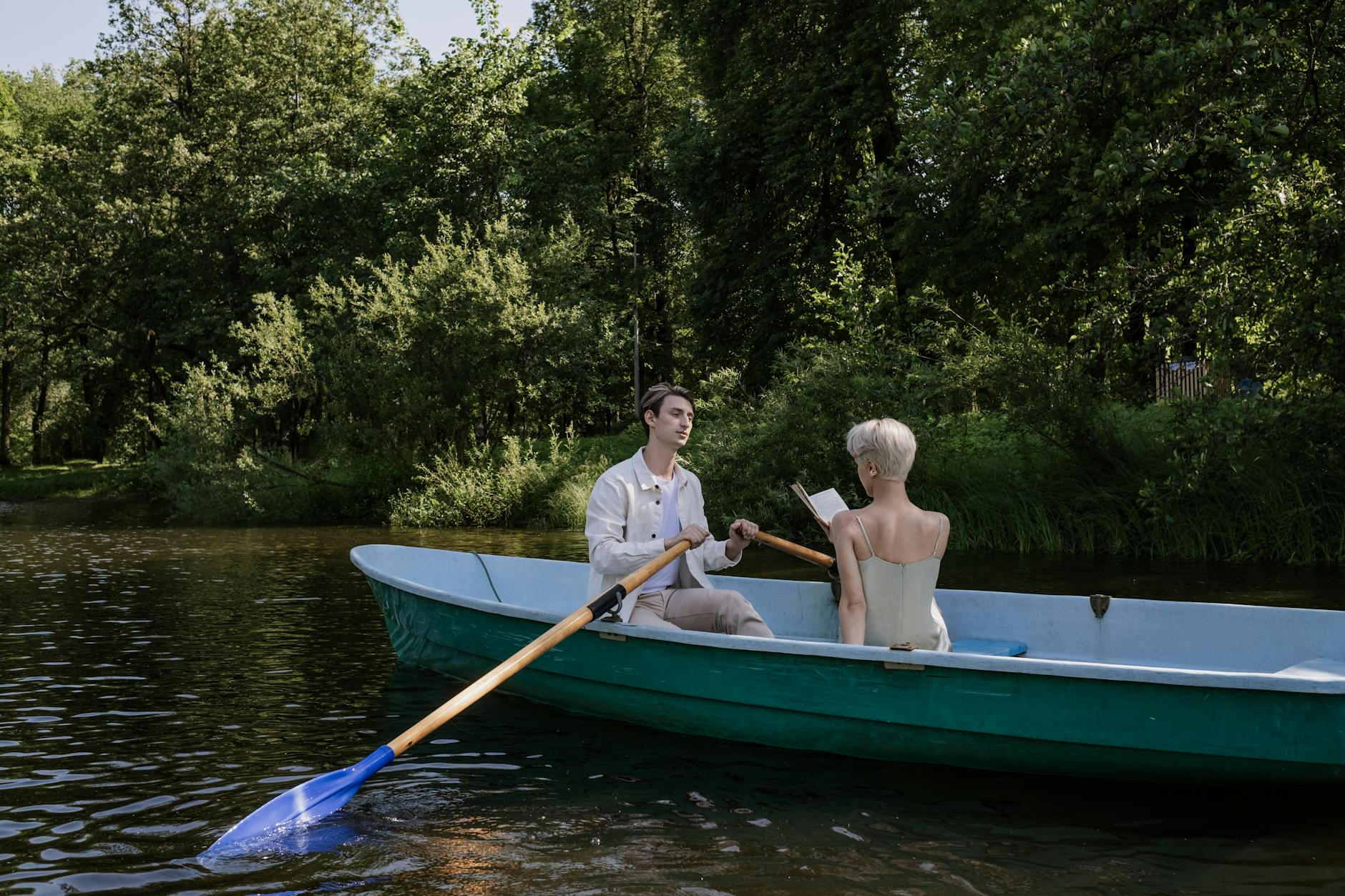 A couple rowing a boat on a peaceful lake surrounded by greenery