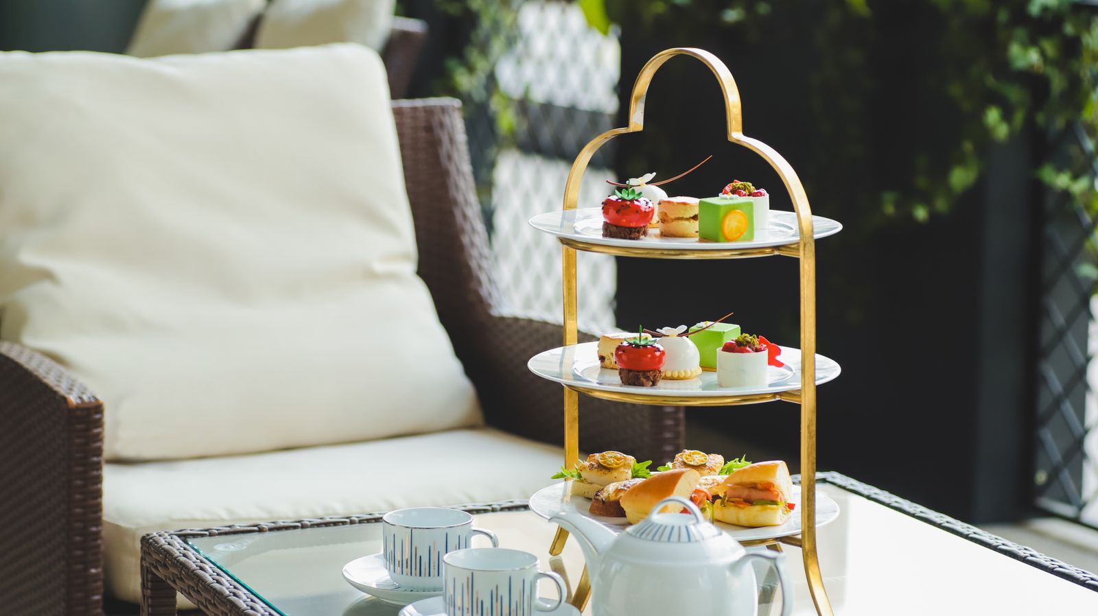 A luxurious afternoon tea with cakes and treats on a tiered stand and a porcelain tea set