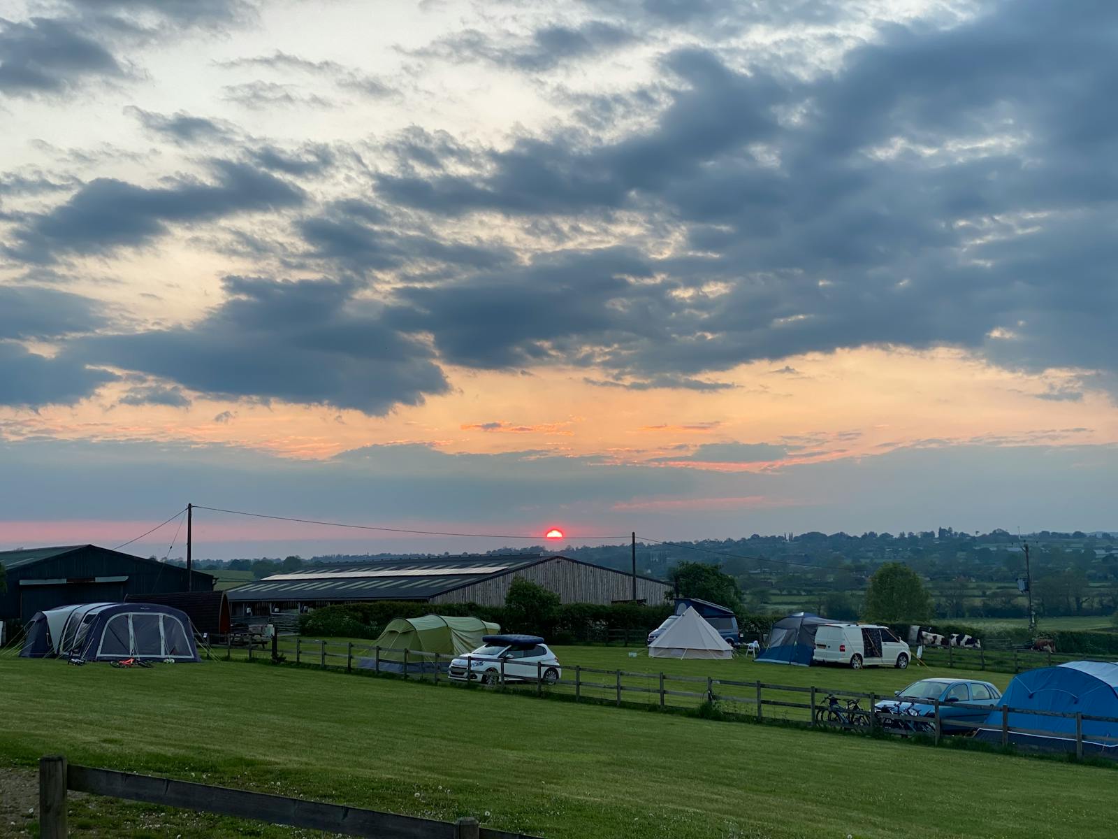 A peaceful rural campsite with tents at sunset