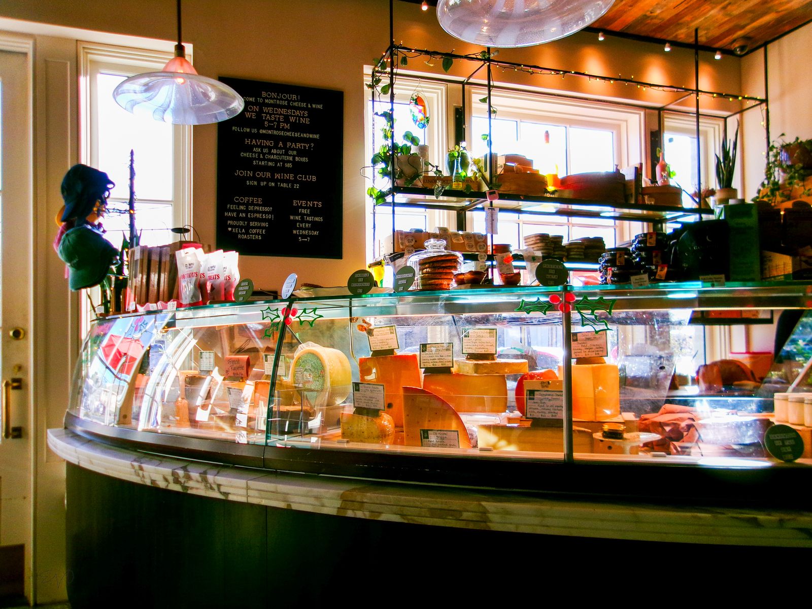 A well-stocked cheese counter at a deli with a variety of cheeses