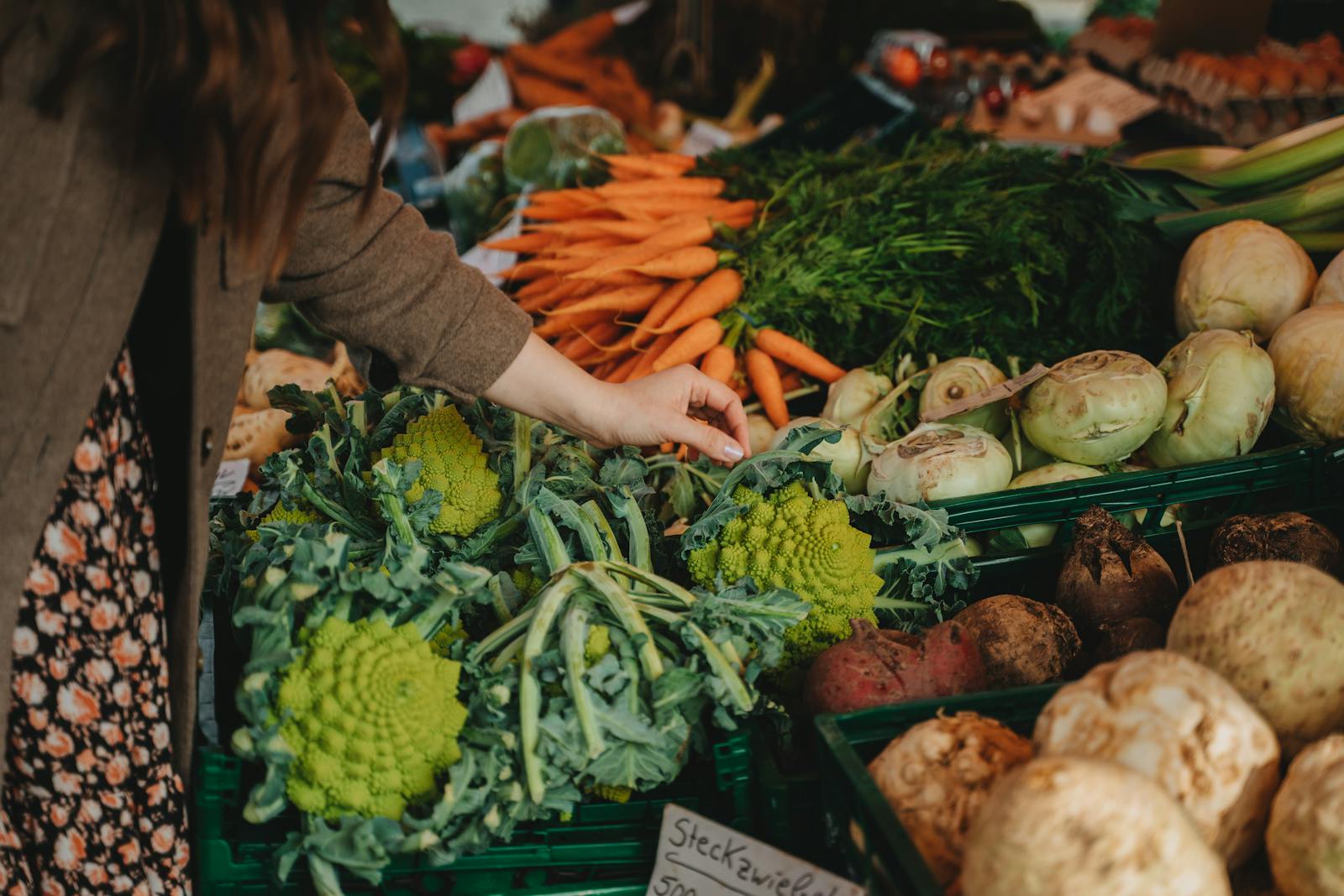 A woman selecting fresh vegetables at a vibrant local farmers market