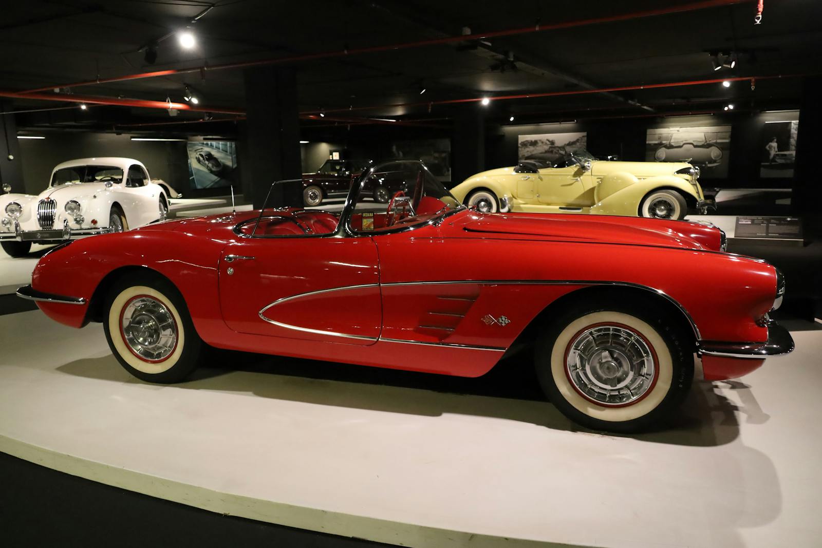 A classic red convertible car displayed in a vintage motoring museum