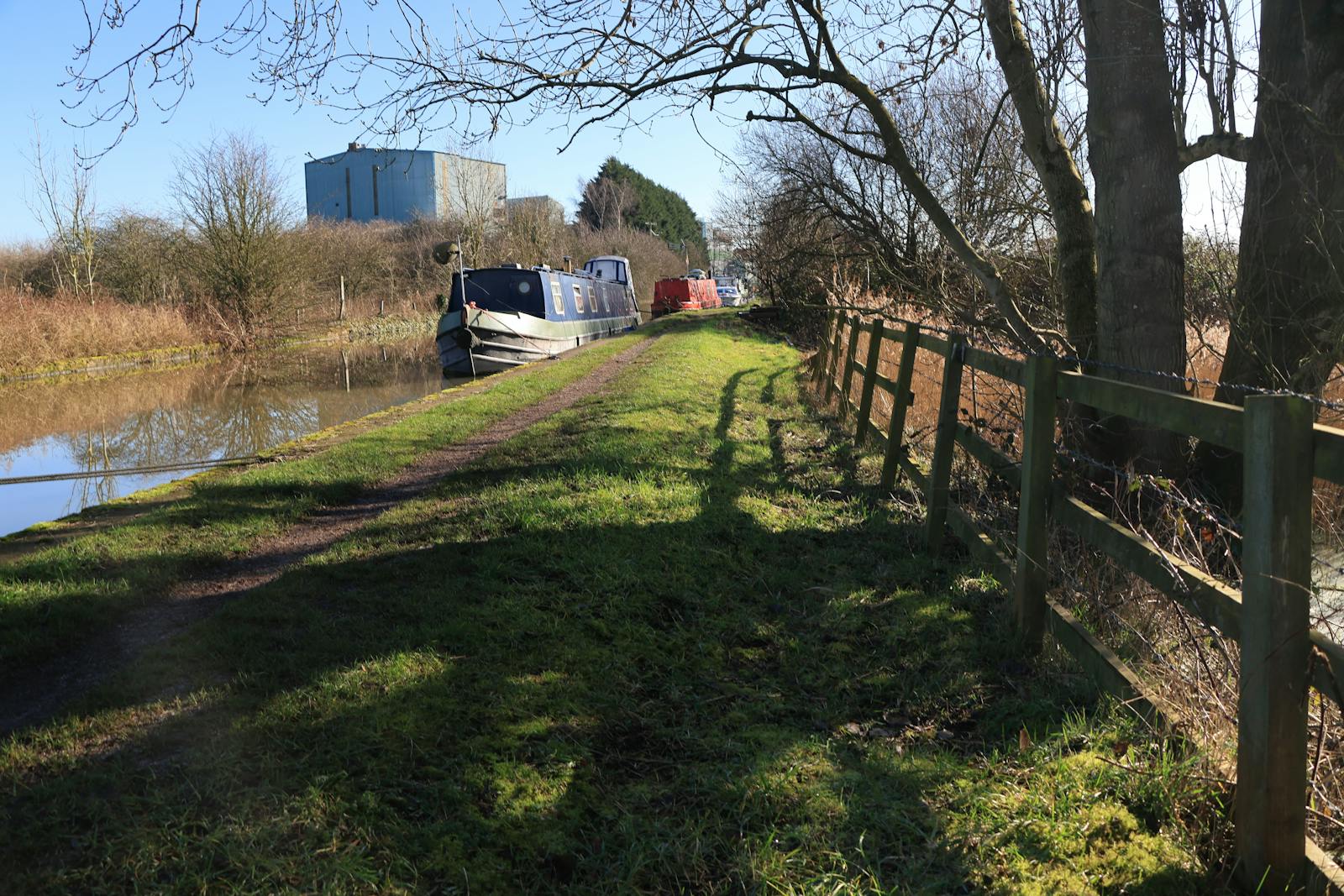 A peaceful canal with a narrowboat on a sunny day, lined with greenery