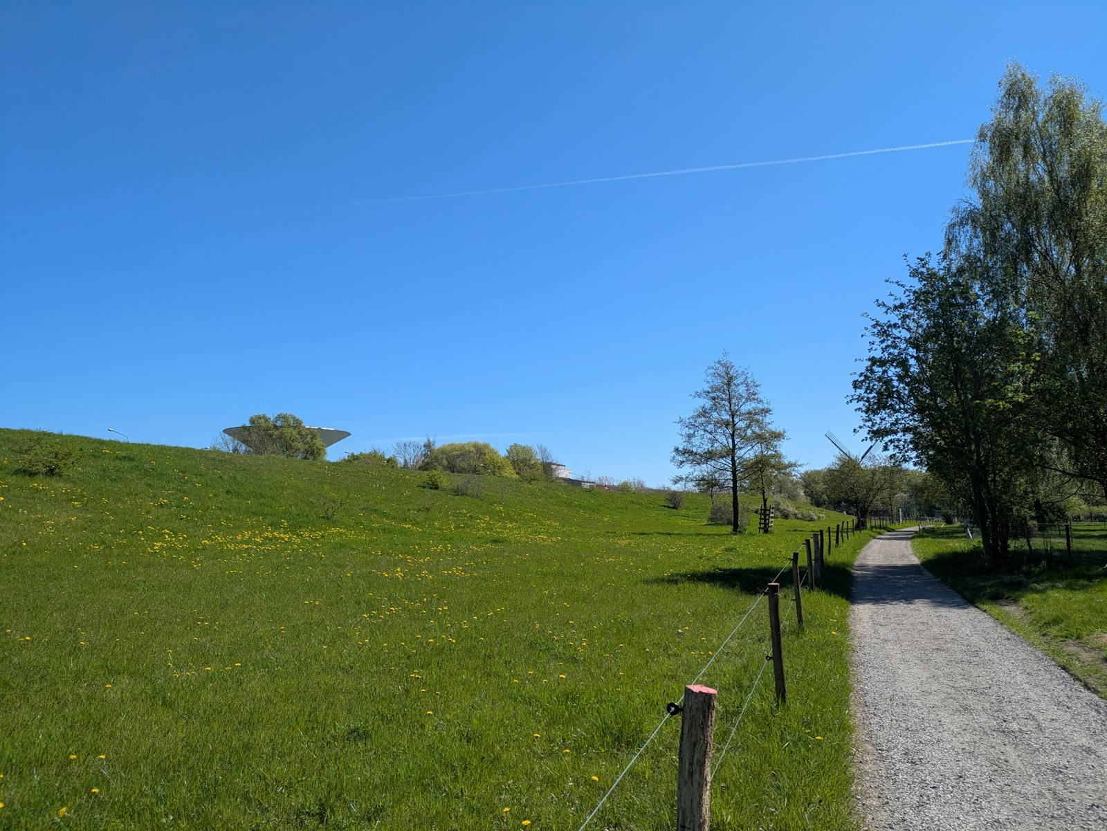 A peaceful gravel path through lush green fields under a bright blue sky