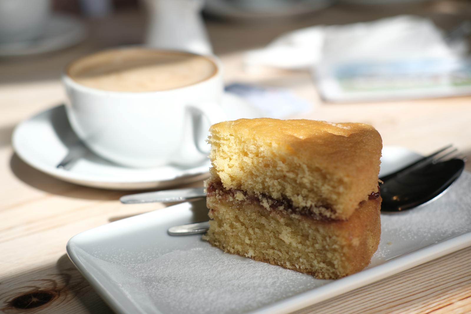 A slice of sponge cake and a cup of coffee in a sunlit cafe