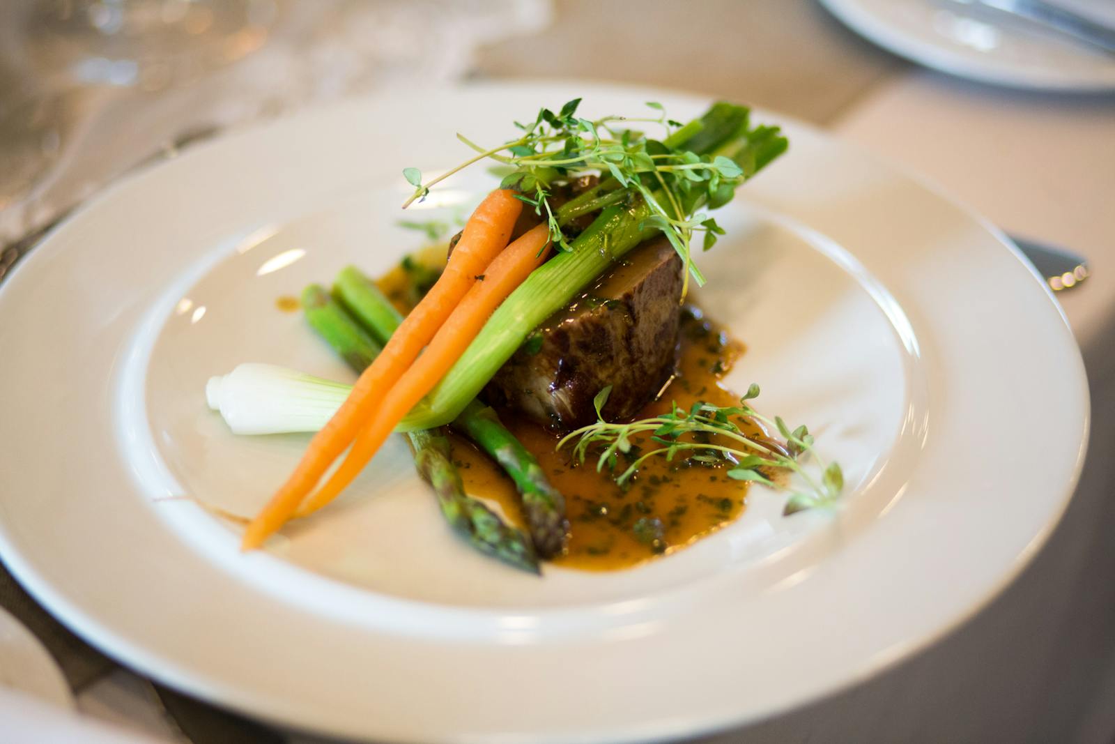 A luxurious gourmet dish elegantly plated with vegetables and sauce