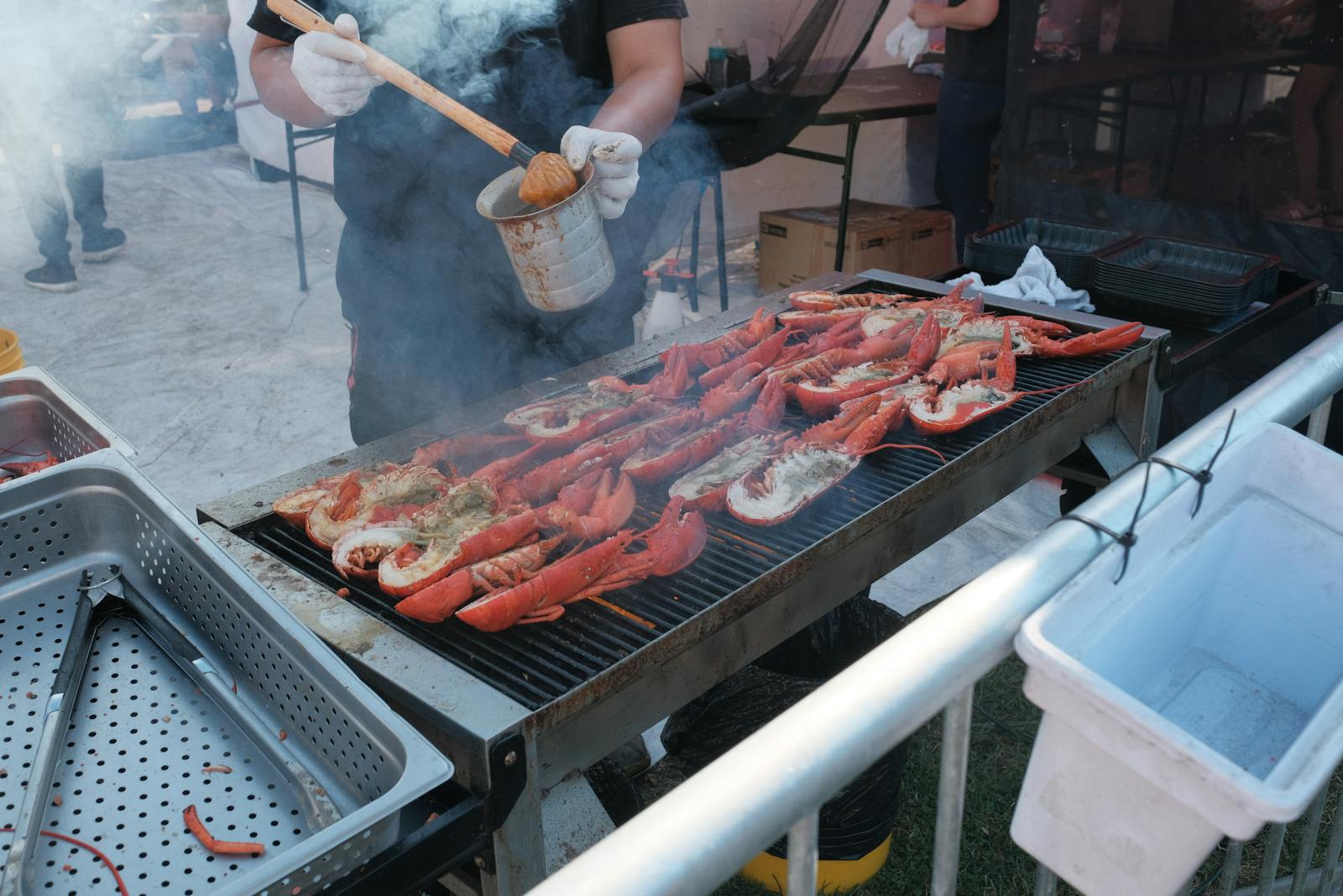 Food being grilled at a lively outdoor food event with smoke rising