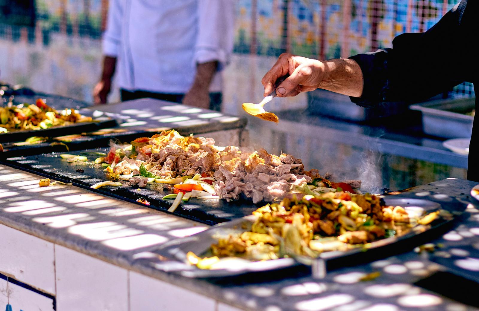 A chef cooking sizzling meat and vegetables at a busy street food stall