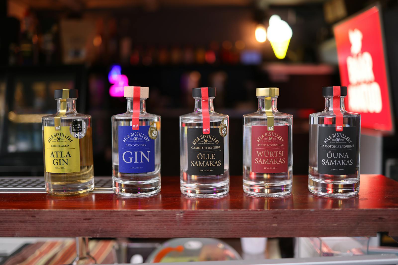 A row of artisan gin bottles displayed on a wooden bar counter
