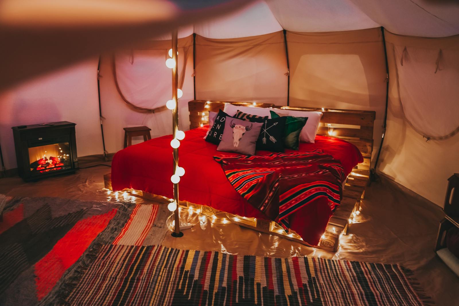 An inviting glamping tent interior with cosy string lights and comfortable bedding