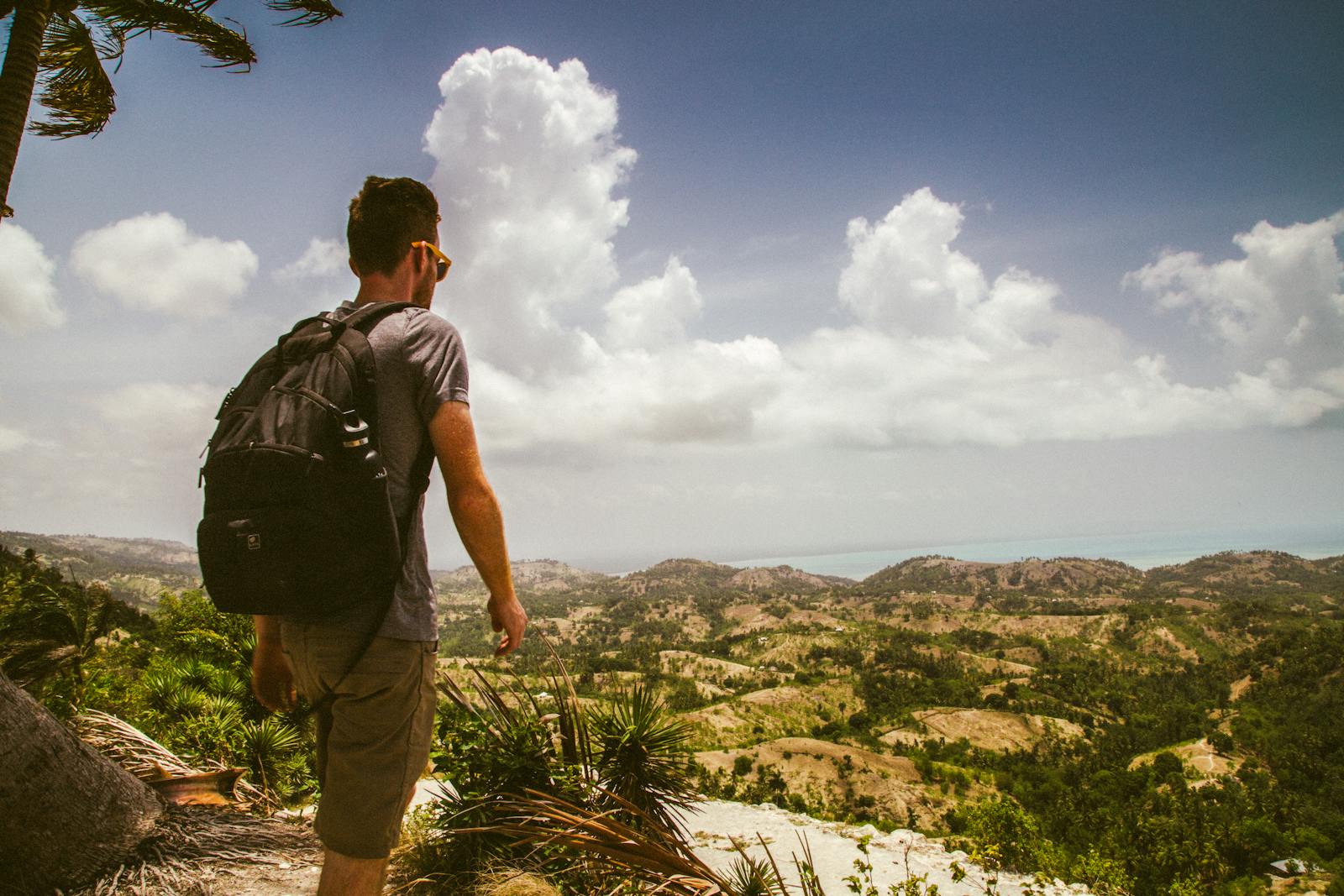 A backpacker walking through a vast open landscape under a bright sky