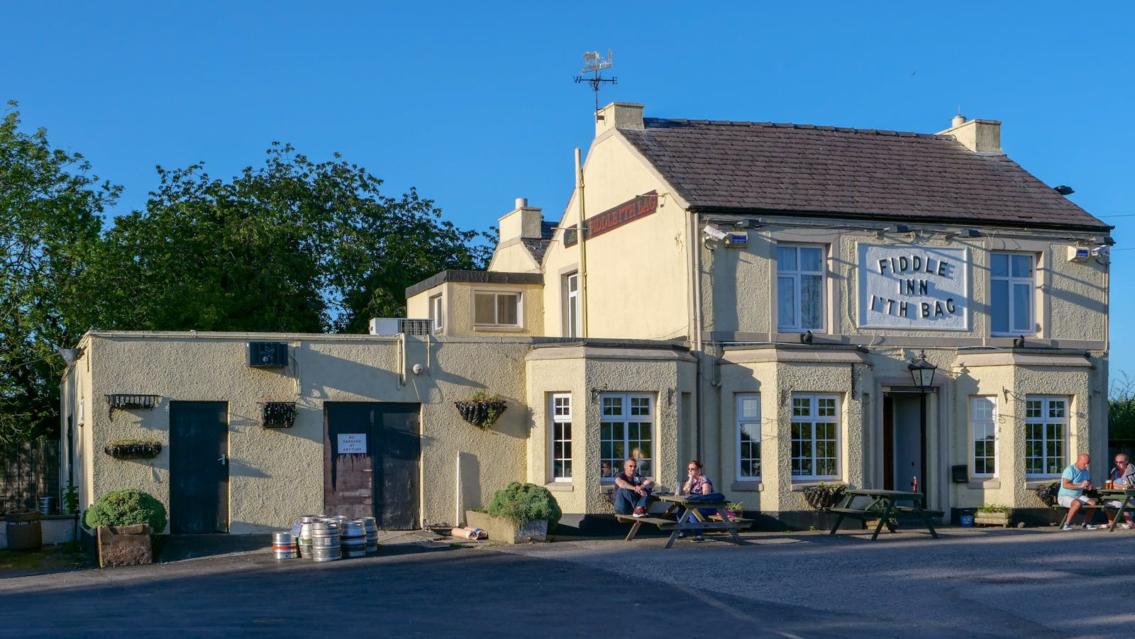 A traditional British country pub with people enjoying a sunny summer day