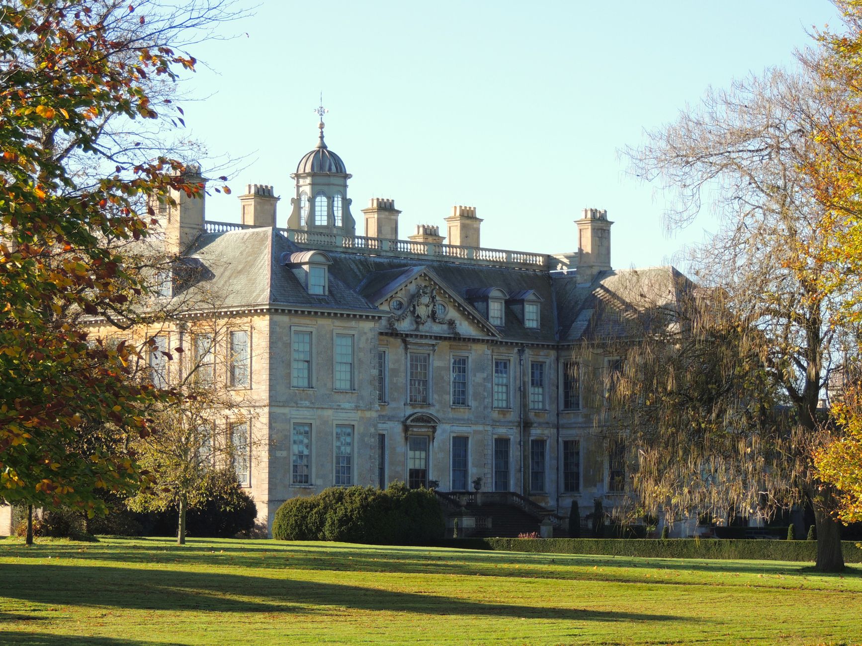 A grand Cotswold manor house and gardens in autumn