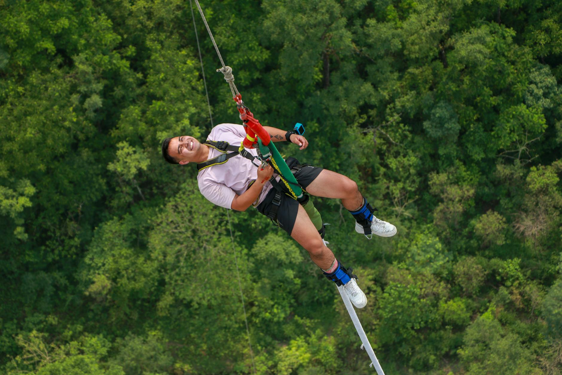 A person zip lining through the treetops over a dense green forest