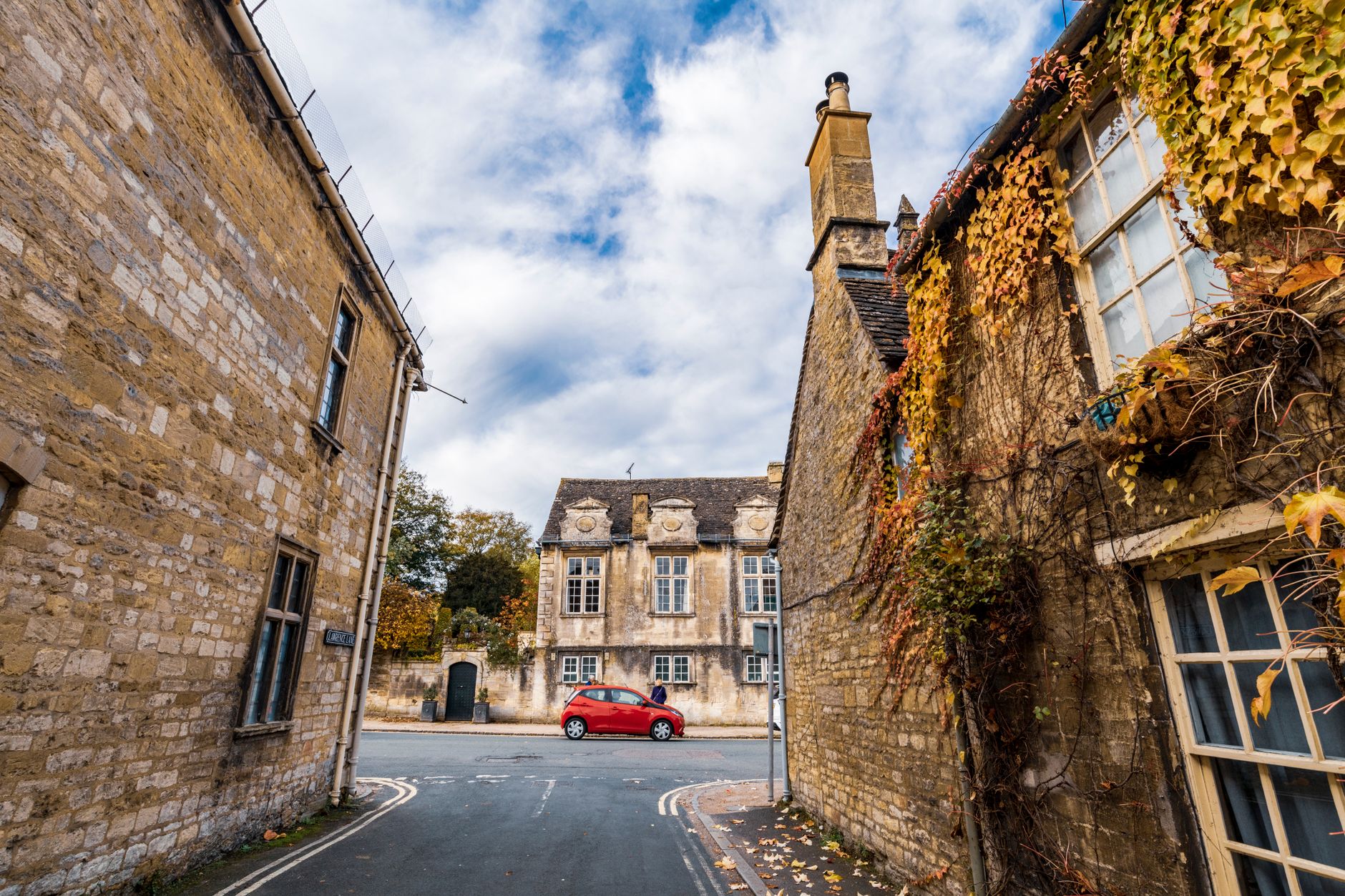 Golden stone buildings lining Burford's broad High Street in autumn light