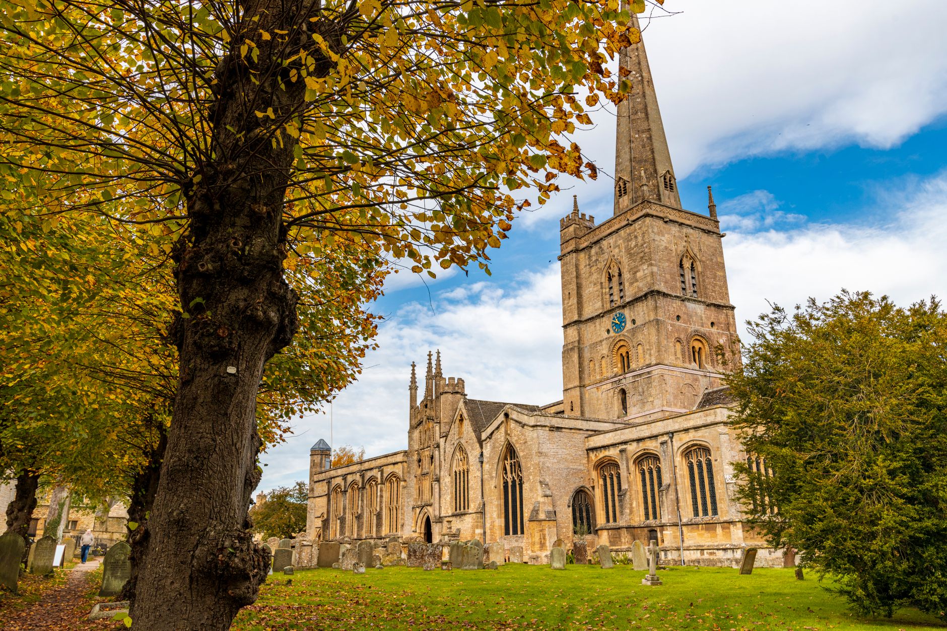 The medieval tower of St John the Baptist Church rising above trees in Burford