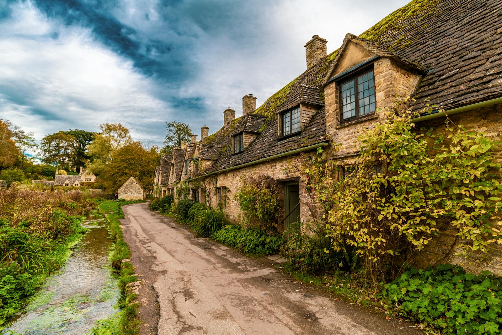 Honey-coloured Cotswold stone cottages lining a lane in Bibury, England