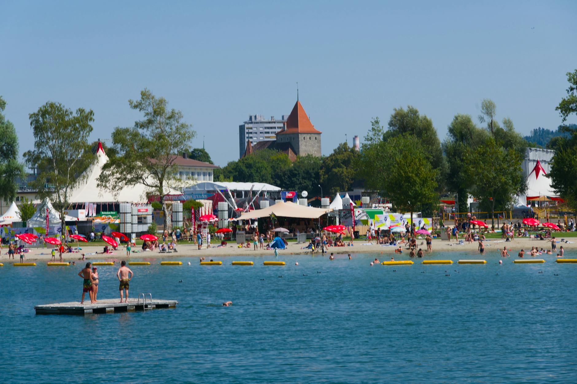 People enjoying a sunny day at an inland lake beach with swimming and activities