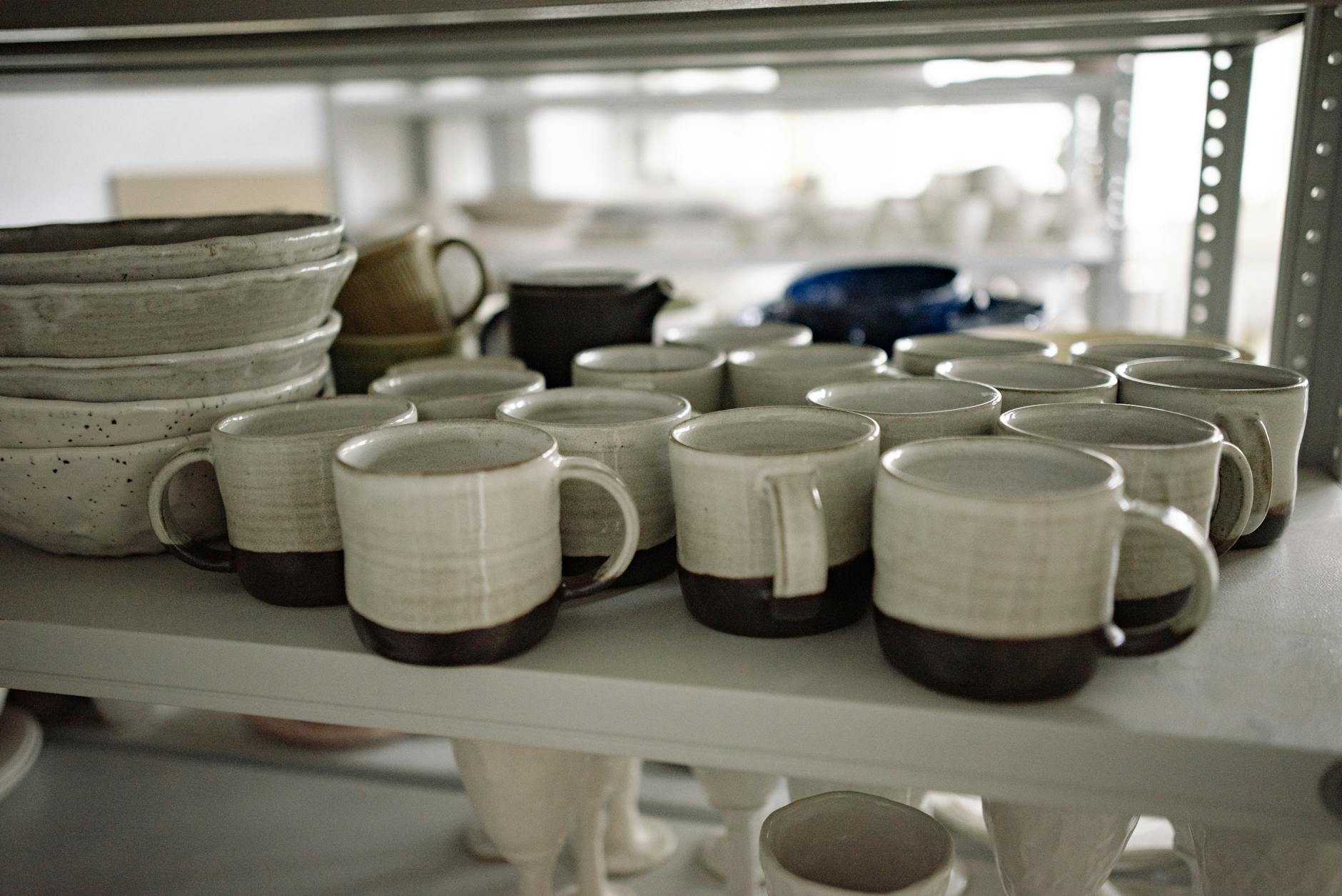 Handmade ceramic mugs on a shelf at a Cotswolds craft studio