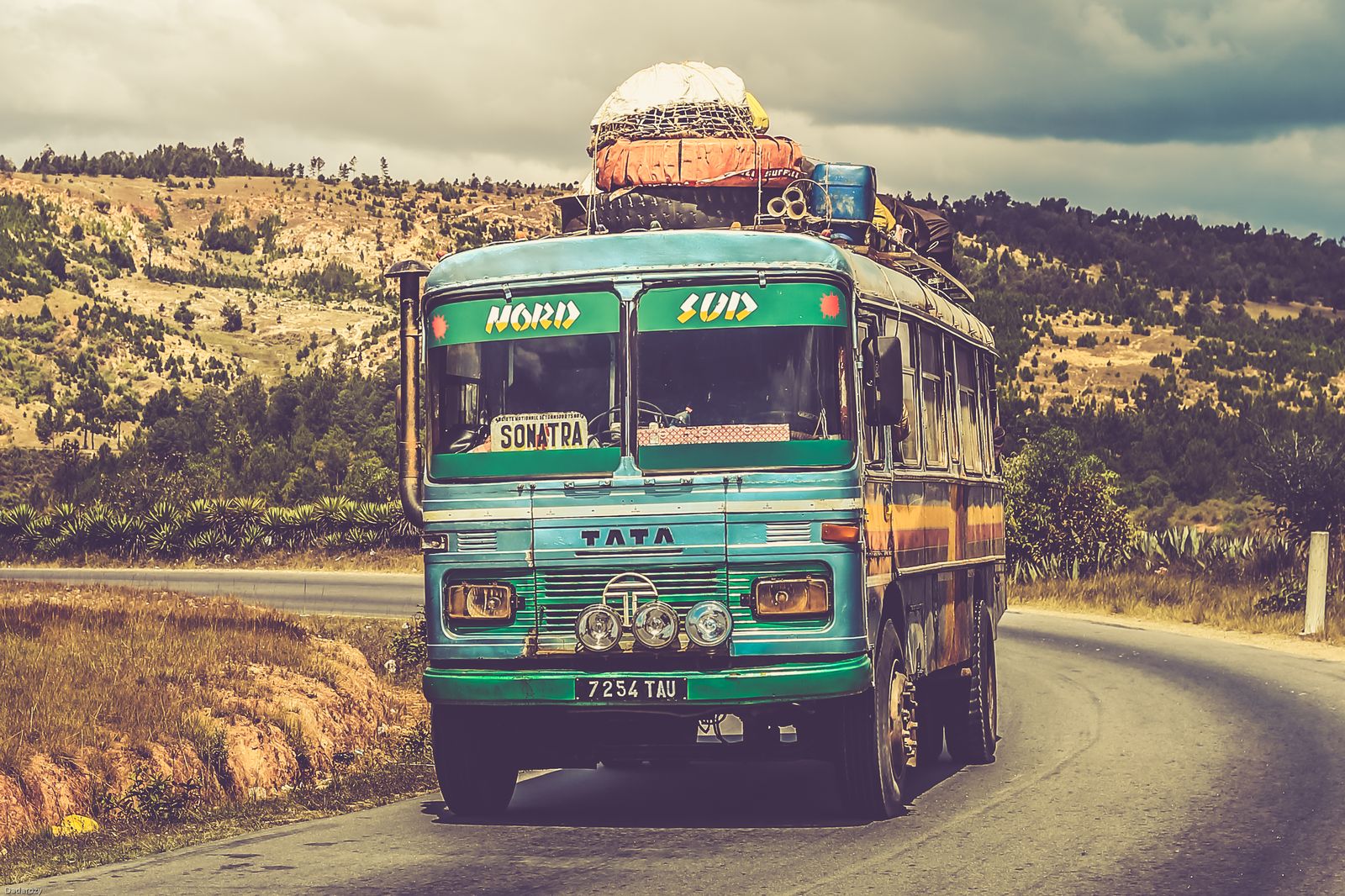 A colourful bus travelling on a scenic countryside road