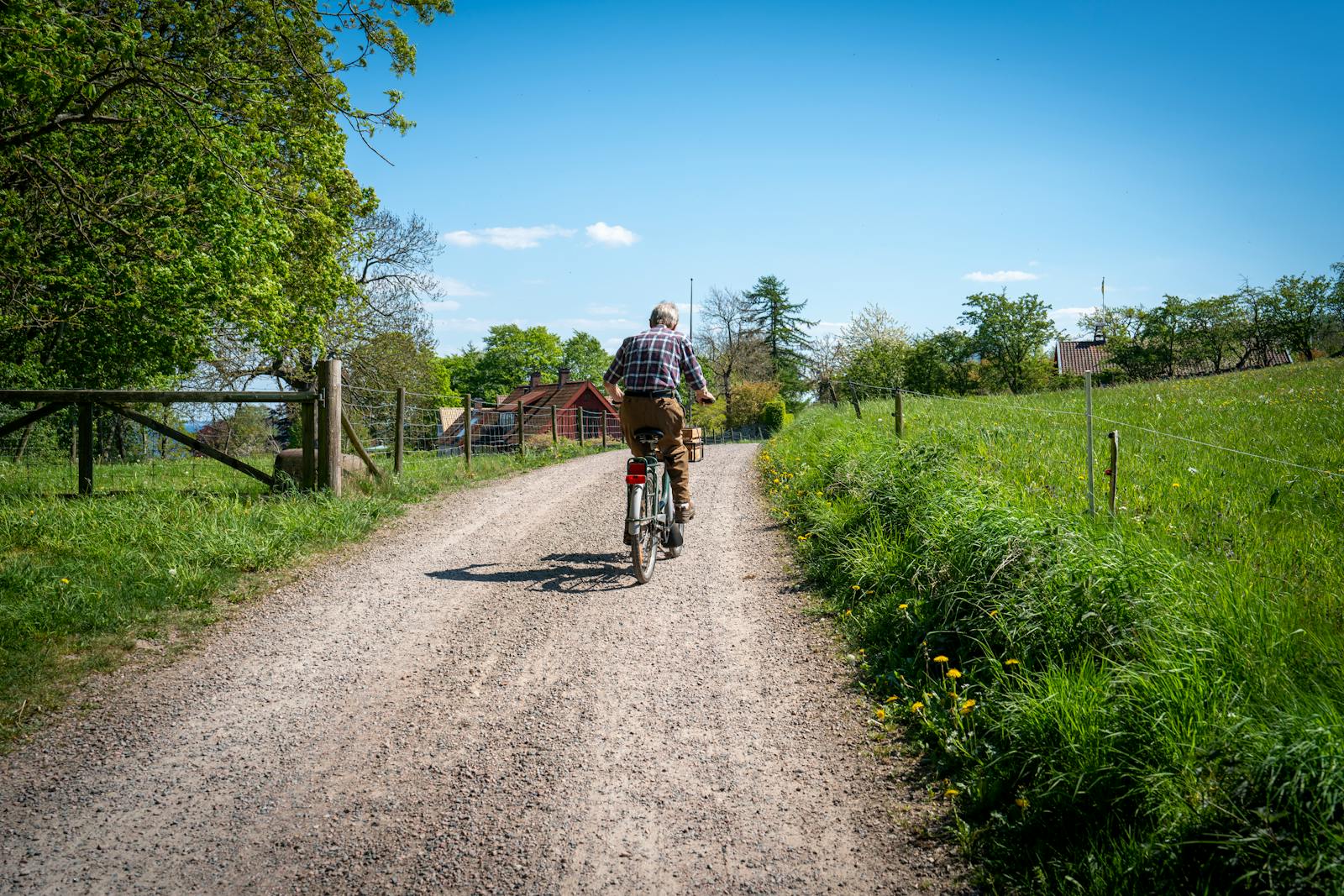 A cyclist riding along a gravel path through the green countryside