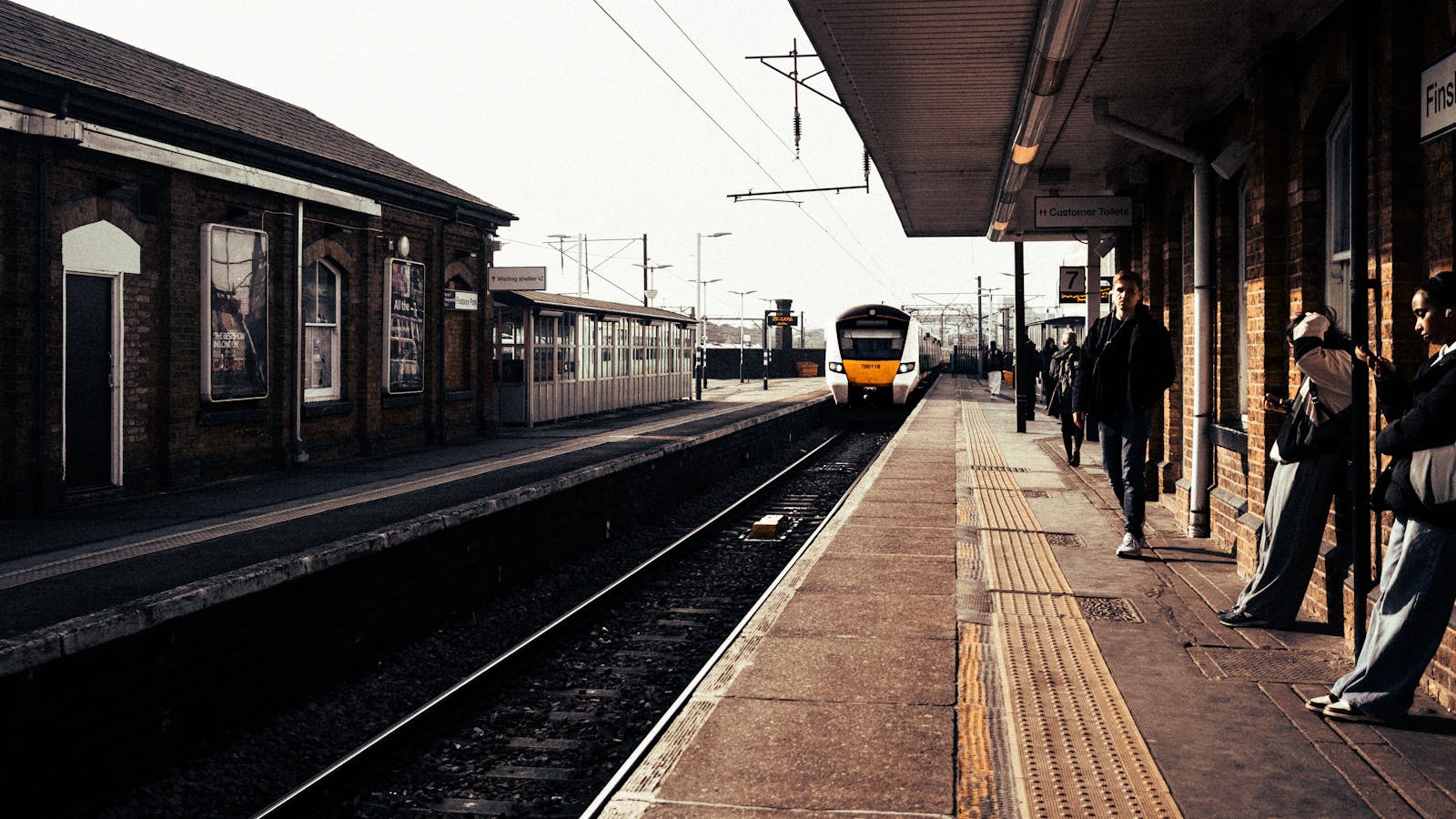Passengers waiting on a platform as a train approaches the station