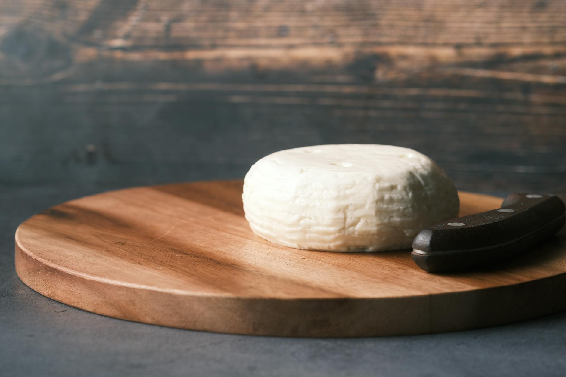 A round wheel of cheese on a rustic wooden board
