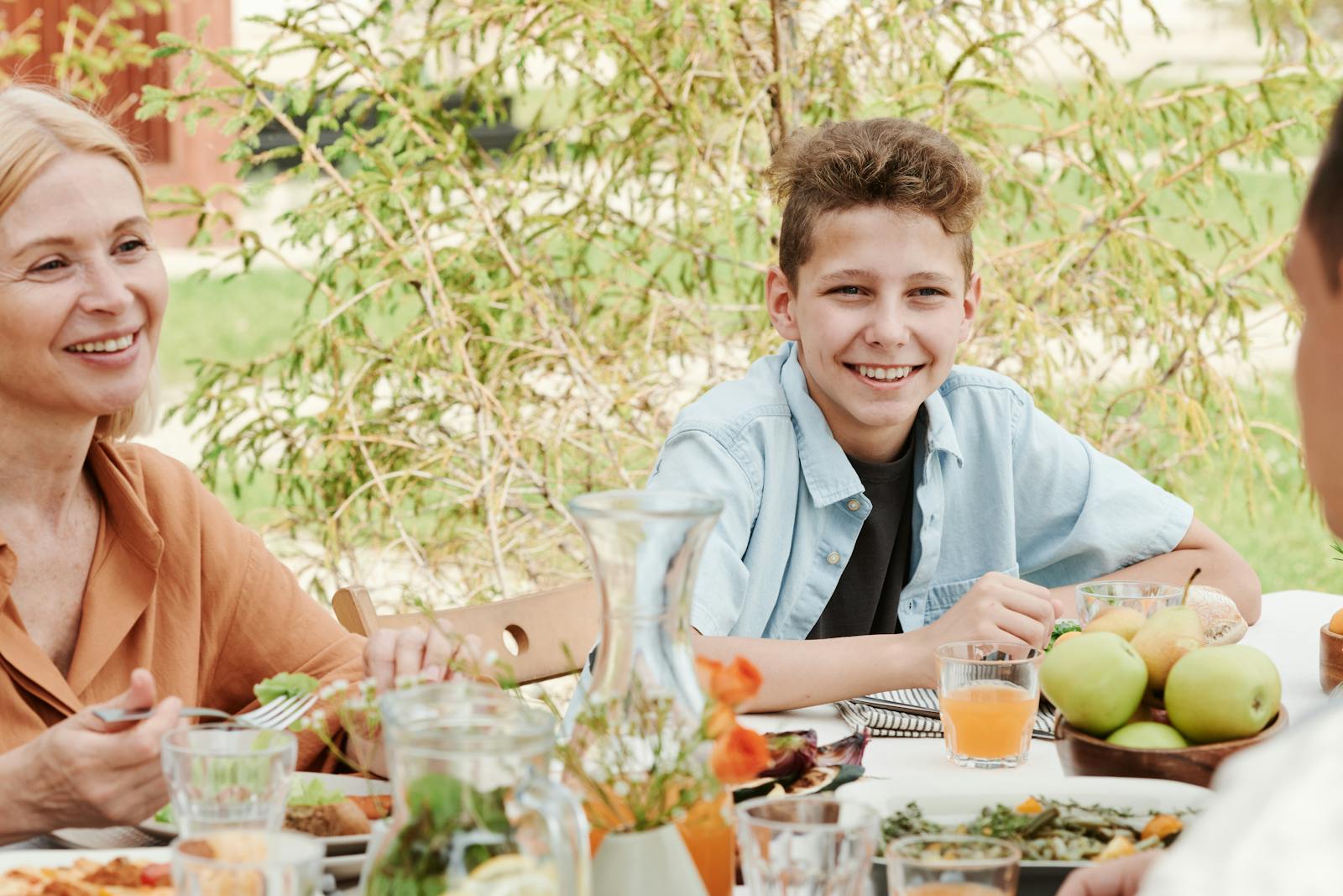 A smiling family of four enjoying a meal together outdoors