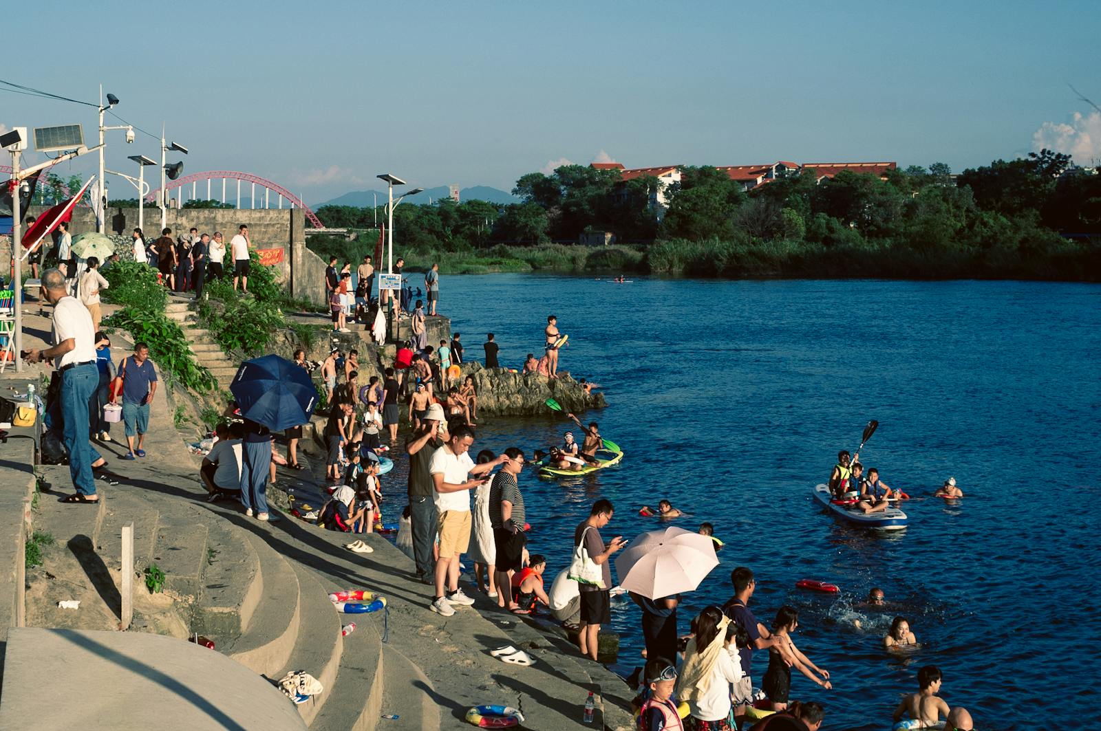 Families gathered at a riverside in a village on a sunny day