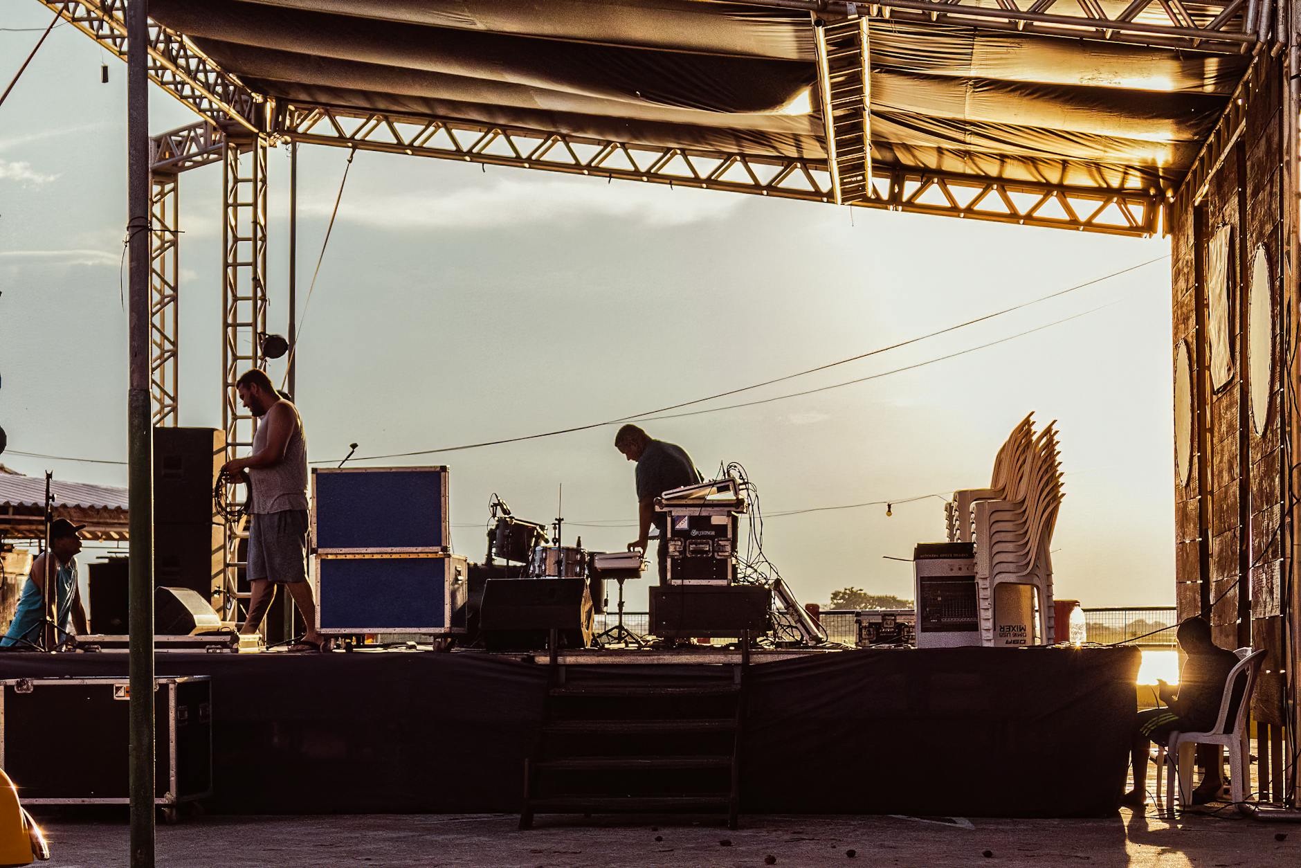 Musicians preparing an outdoor festival stage at sunset
