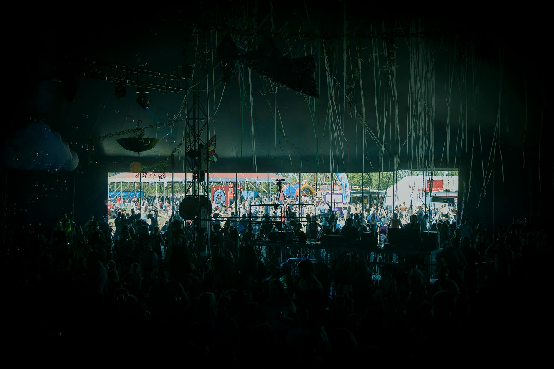 A crowd enjoying live music at a colourful outdoor festival stage in summer