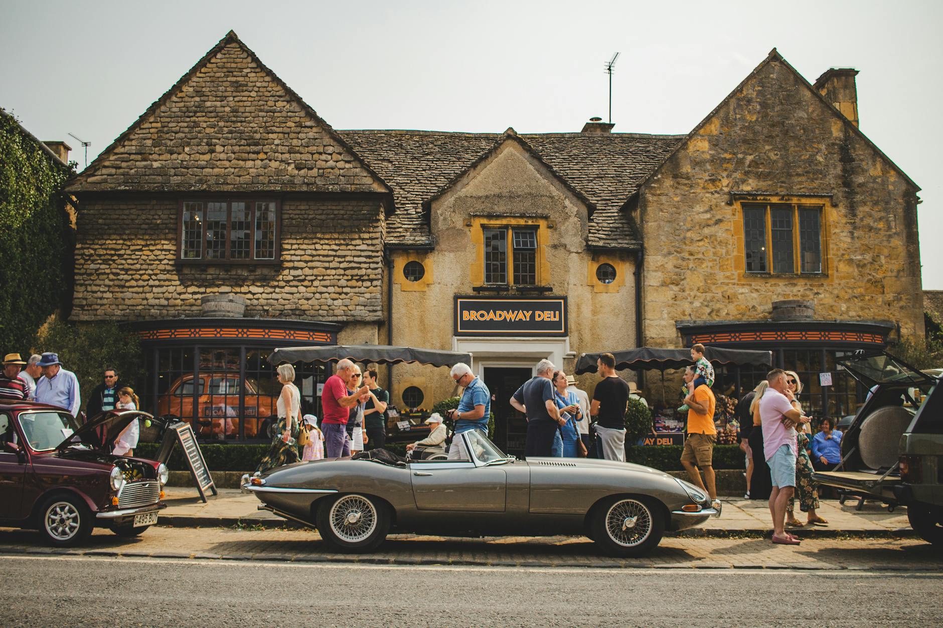 Visitors walking the wide green-verged High Street at Broadway in the Cotswolds