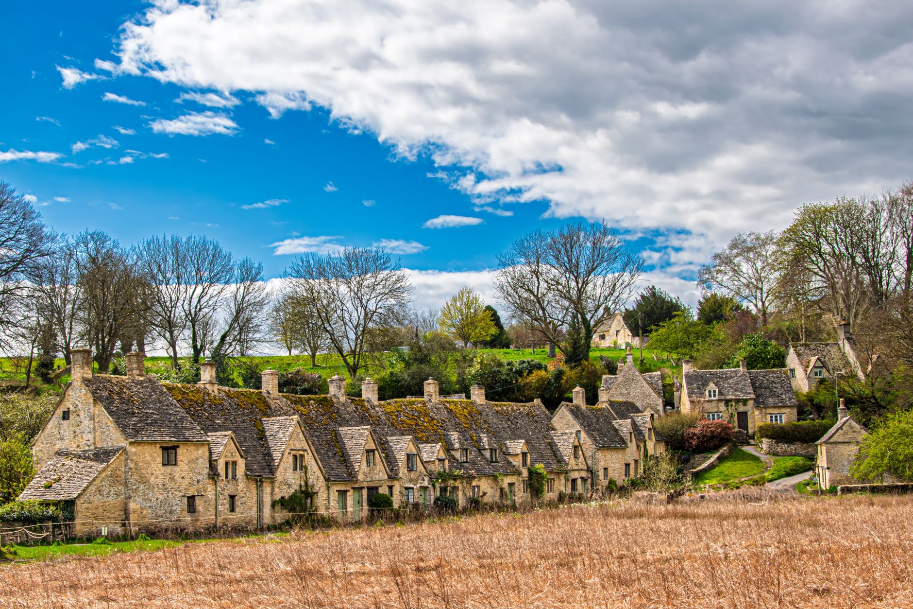 Honey-coloured Cotswold stone village with houses and gardens in spring