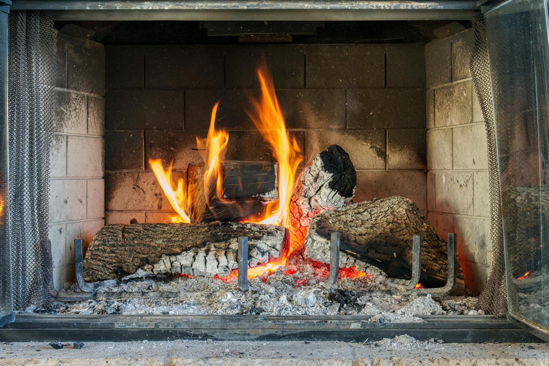 A glowing log fire in a fireplace inside a cosy English pub in winter
