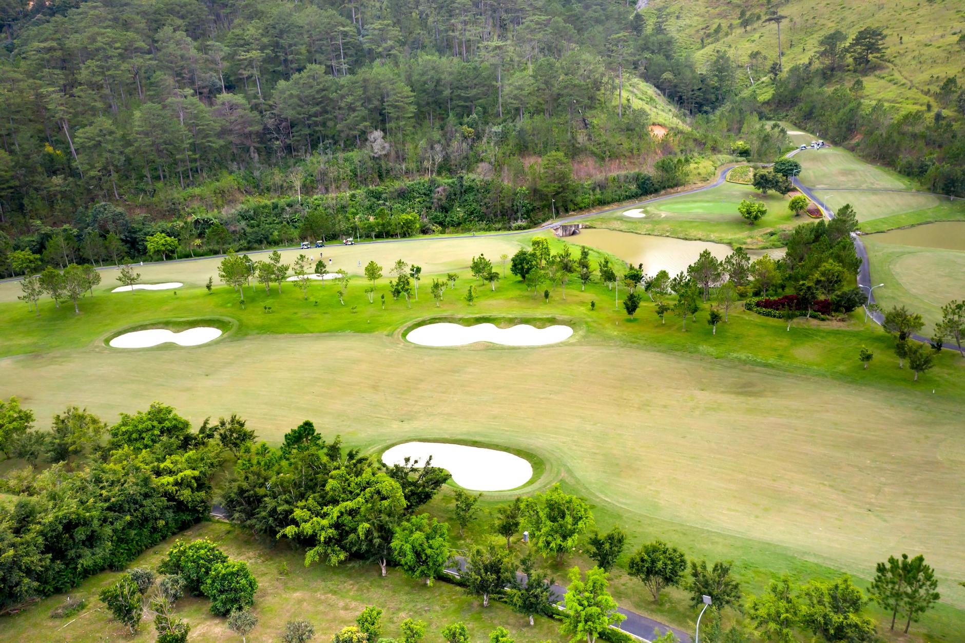 An aerial view of a lush green golf course surrounded by rolling hills and trees