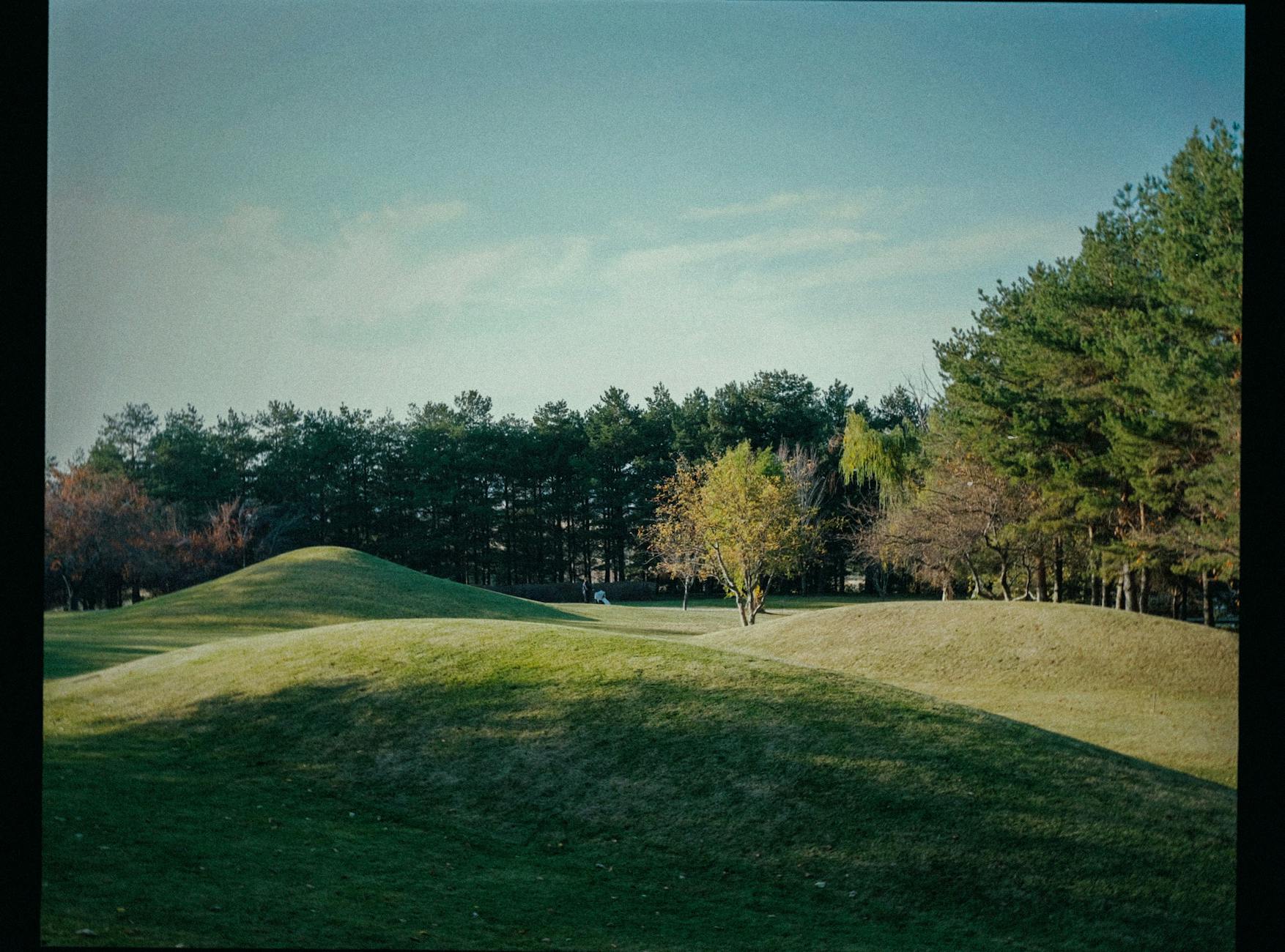 A golf course fairway running through rolling hills with autumn trees