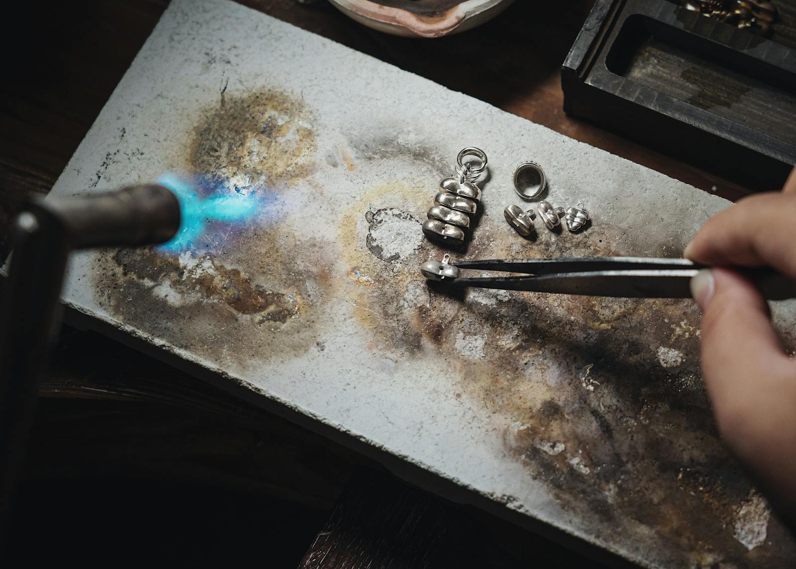 A silversmith using a torch to craft silver jewellery by hand in a workshop