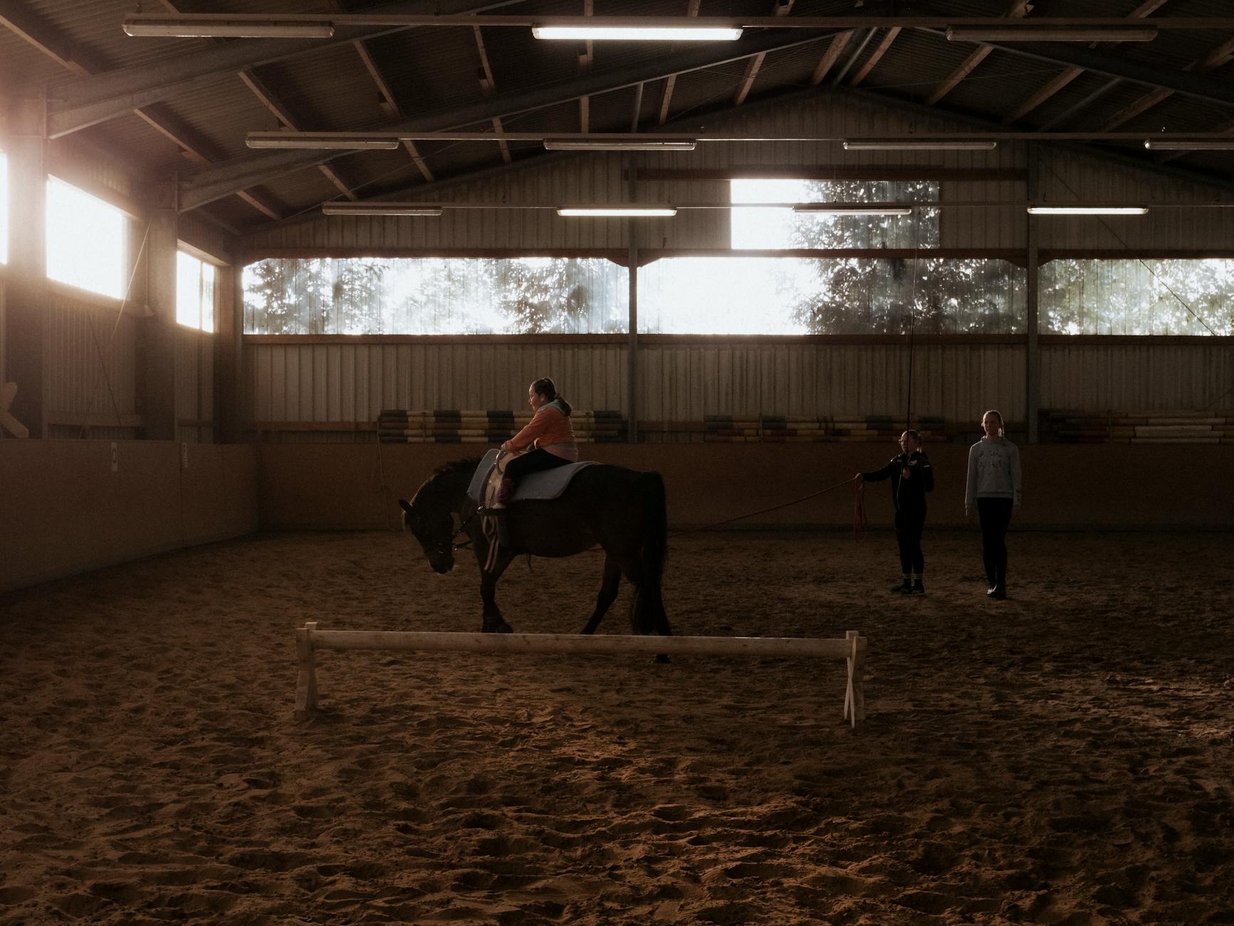 An instructor guiding a beginner during a horse riding lesson