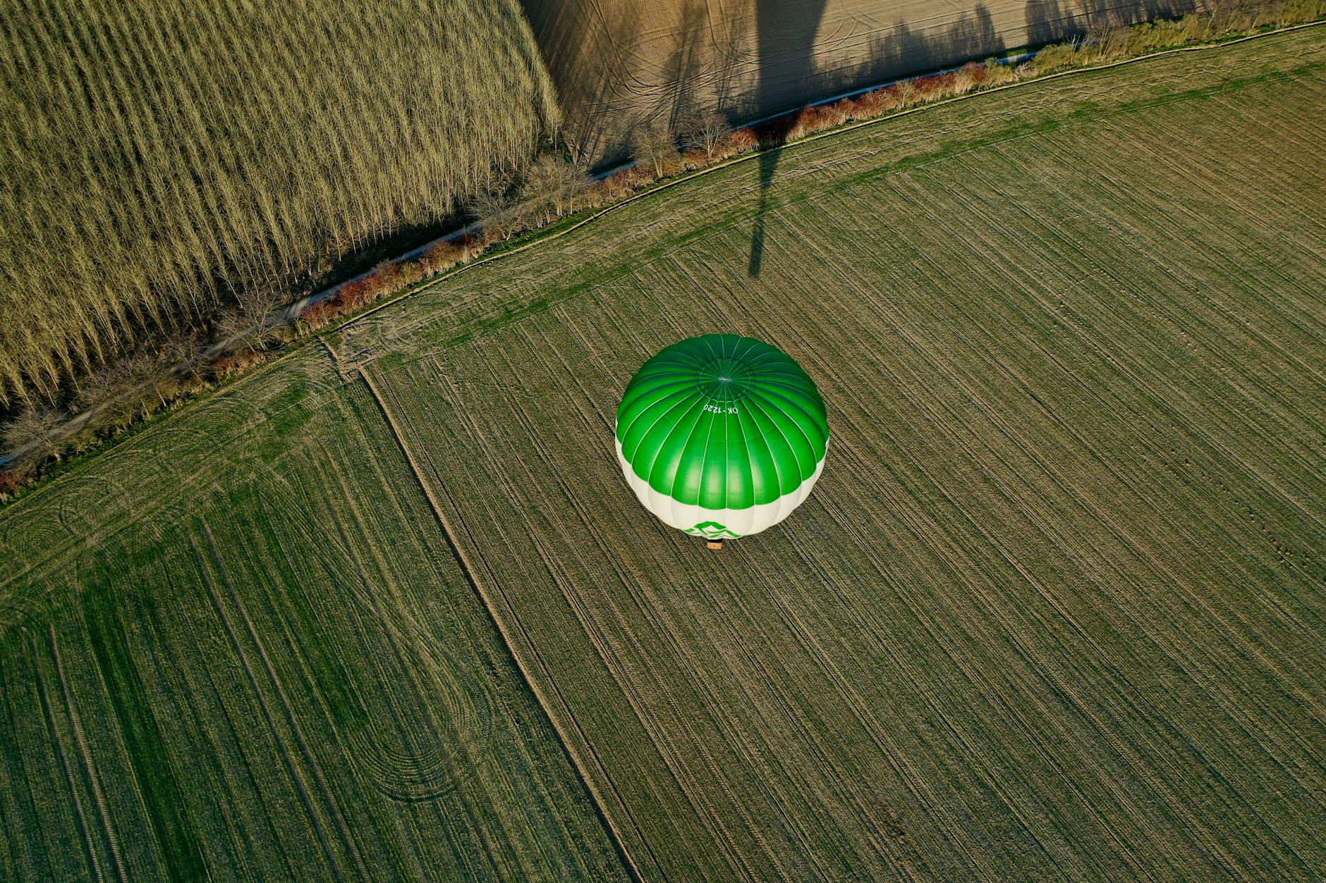 Aerial view of a hot air balloon floating above a patchwork of farmland fields