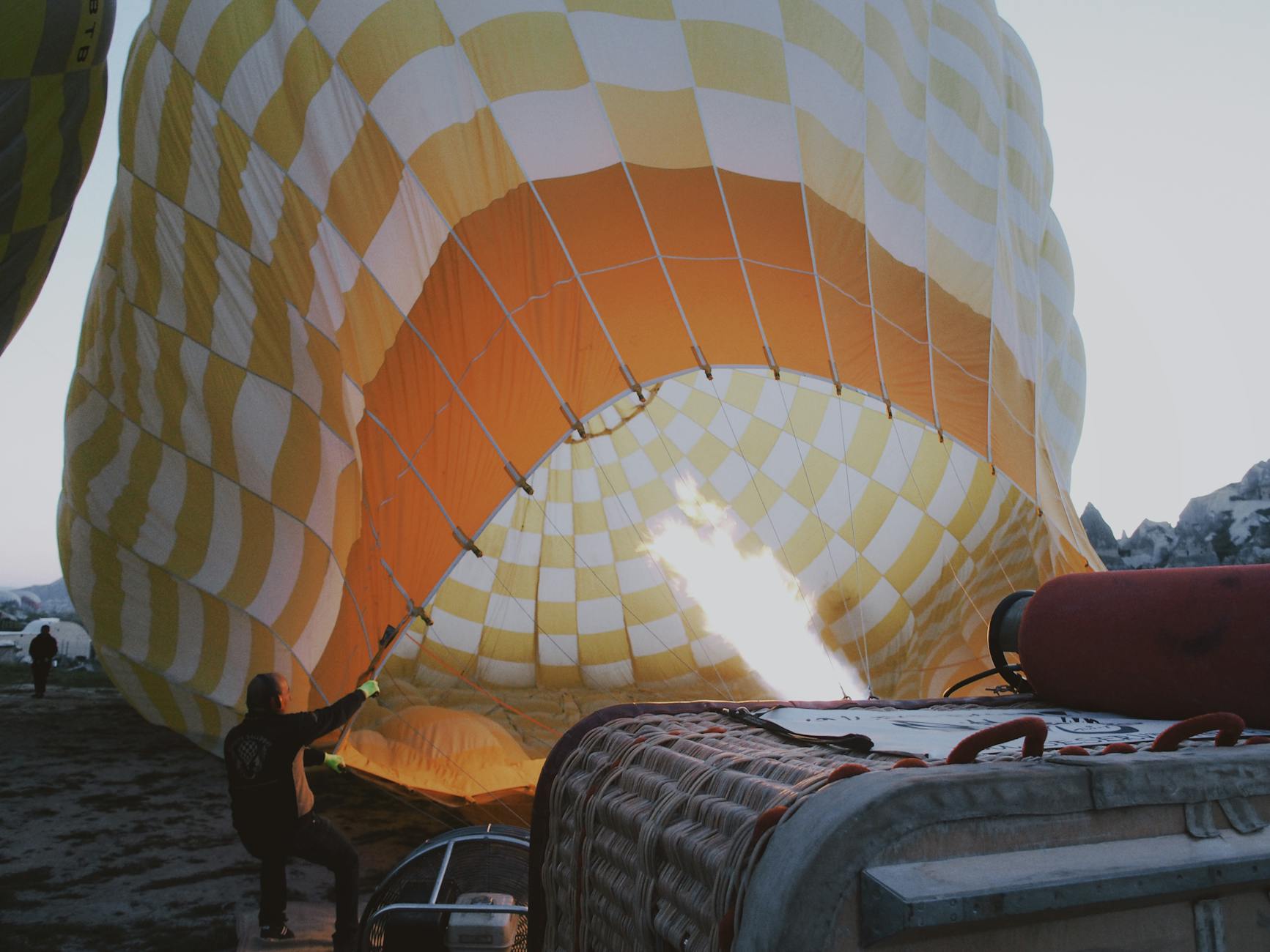 A hot air balloon being inflated with a burst of flame at dawn