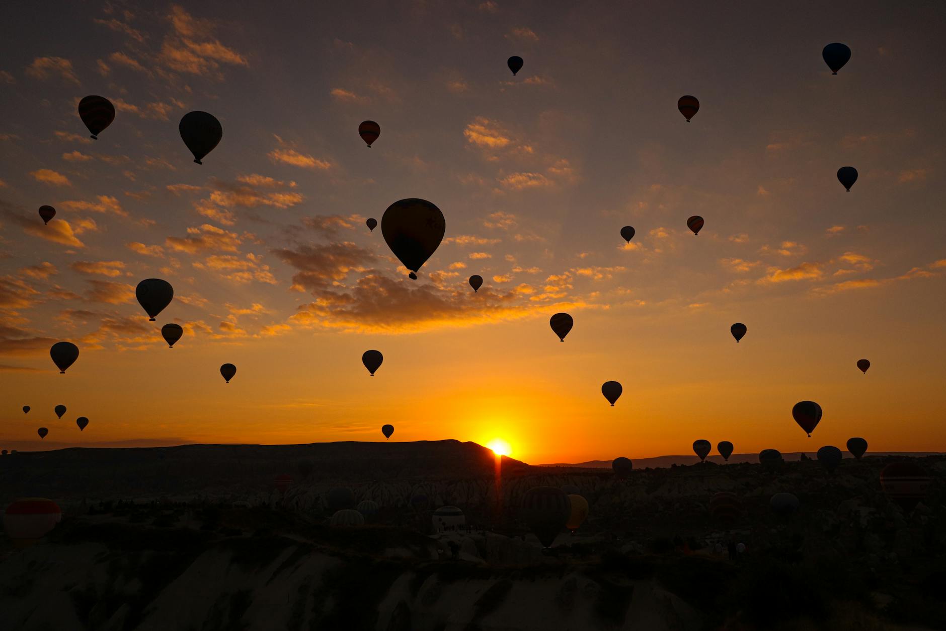 Hot air balloons silhouetted against a golden sunset sky