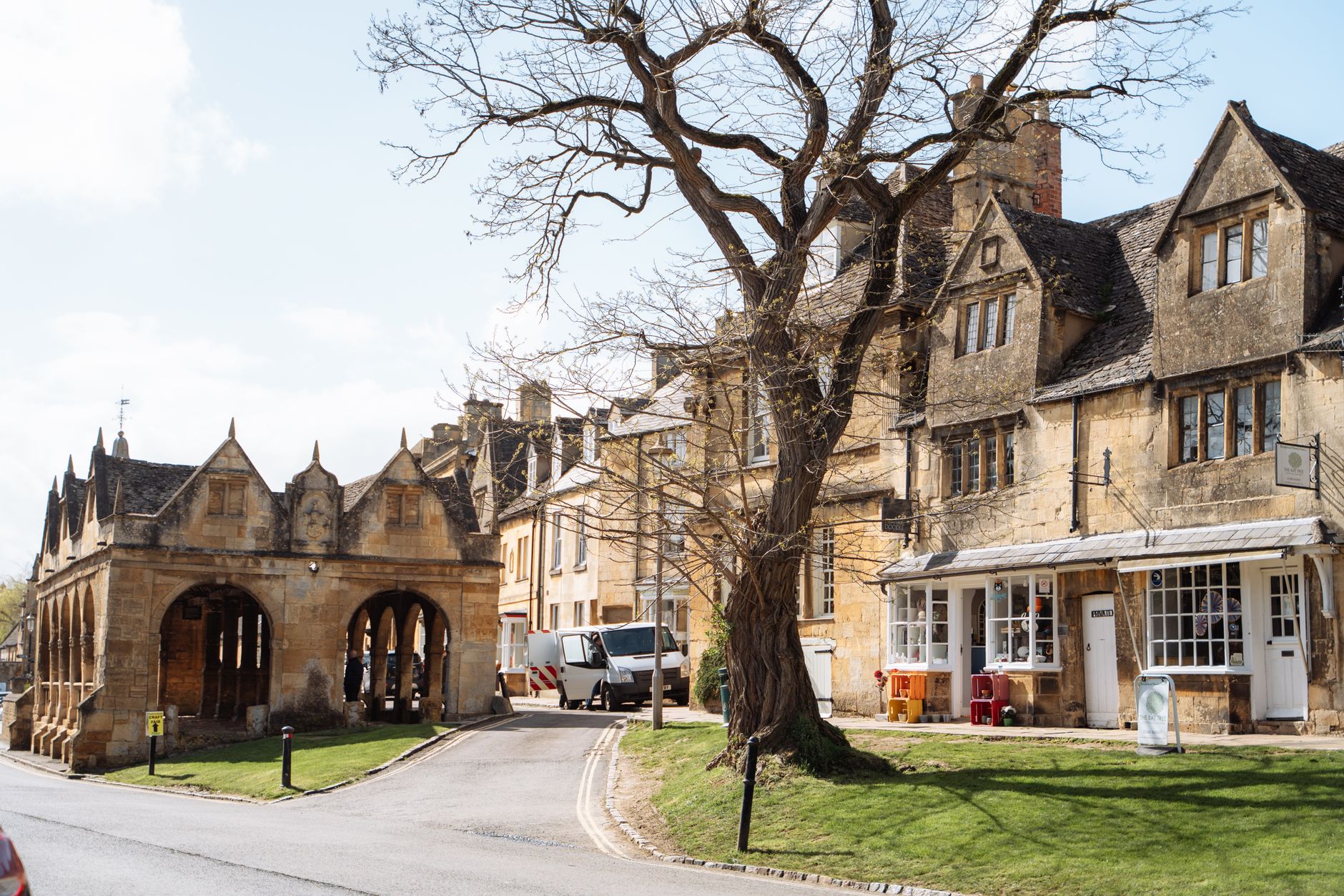 Honey-coloured Cotswold stone buildings and a pillared market hall on a village street