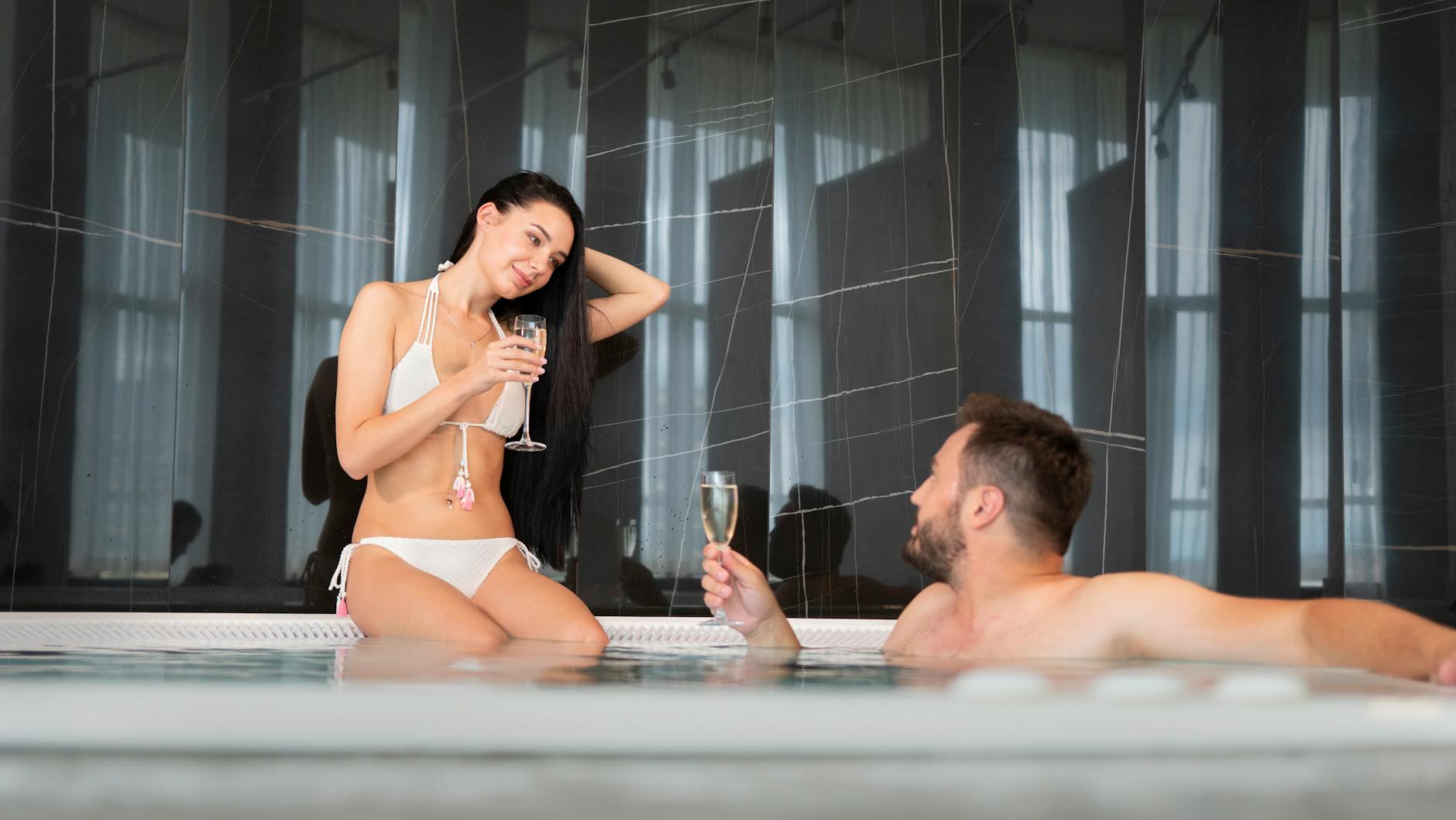 A couple relaxing together in a hot tub with champagne on a romantic break