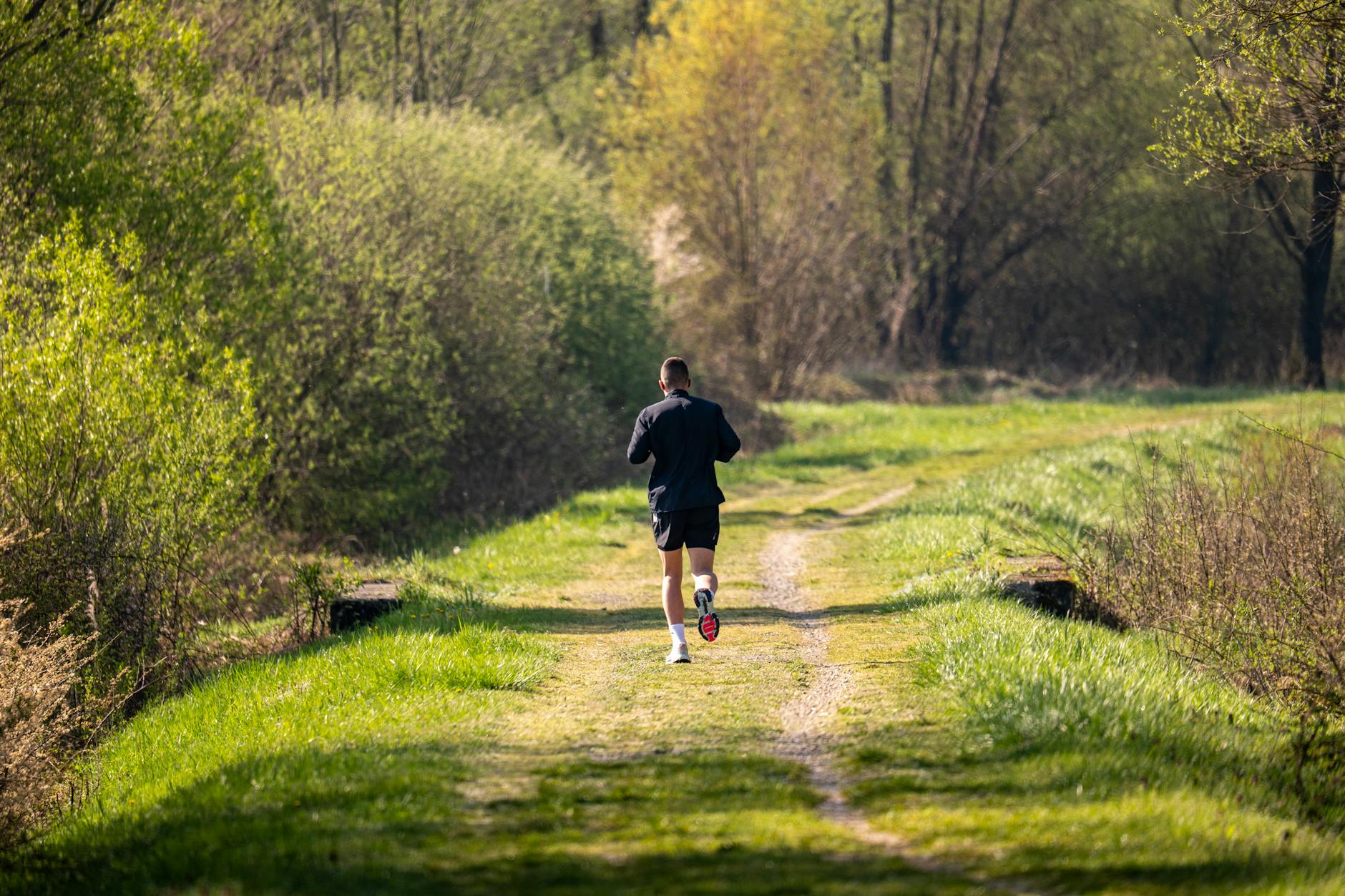 A runner on a grassy trail path surrounded by lush green countryside