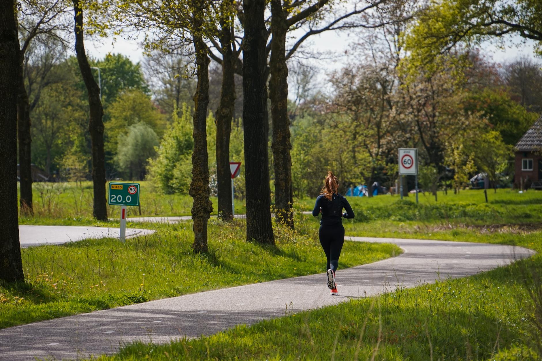 A runner on a winding path through a lush green woodland in spring