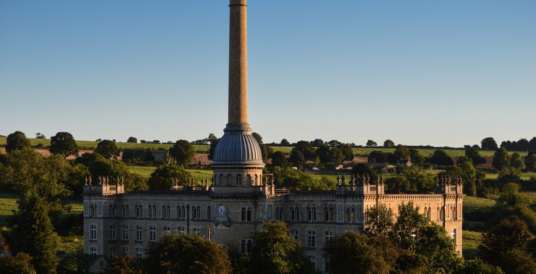 Bliss Tweed Mill at Chipping Norton in evening light, its domed chimney rising above a battlemented stone mill building
