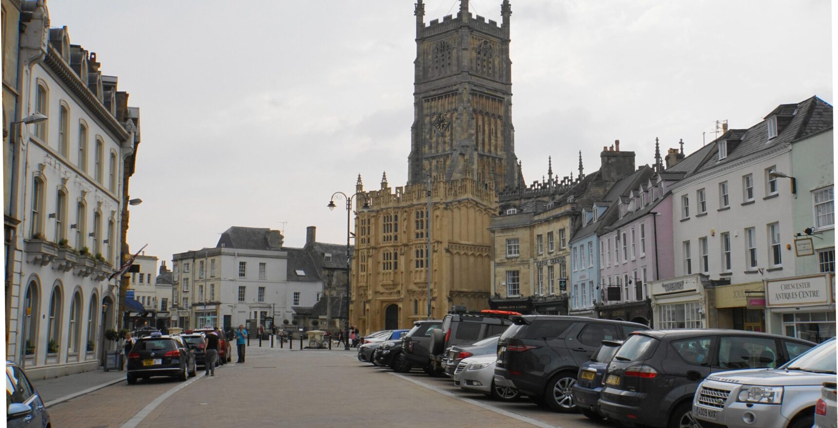 Cirencester Market Place below the tall Perpendicular tower and three-storey porch of St John Baptist church