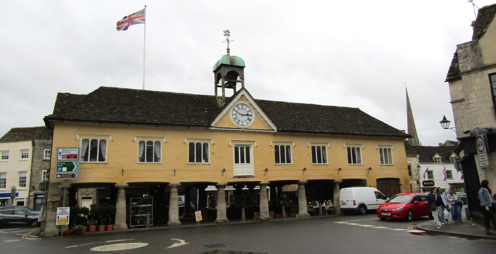 The 1655 Market House at Tetbury standing on stone pillars with a clock, bell turret and the church spire behind